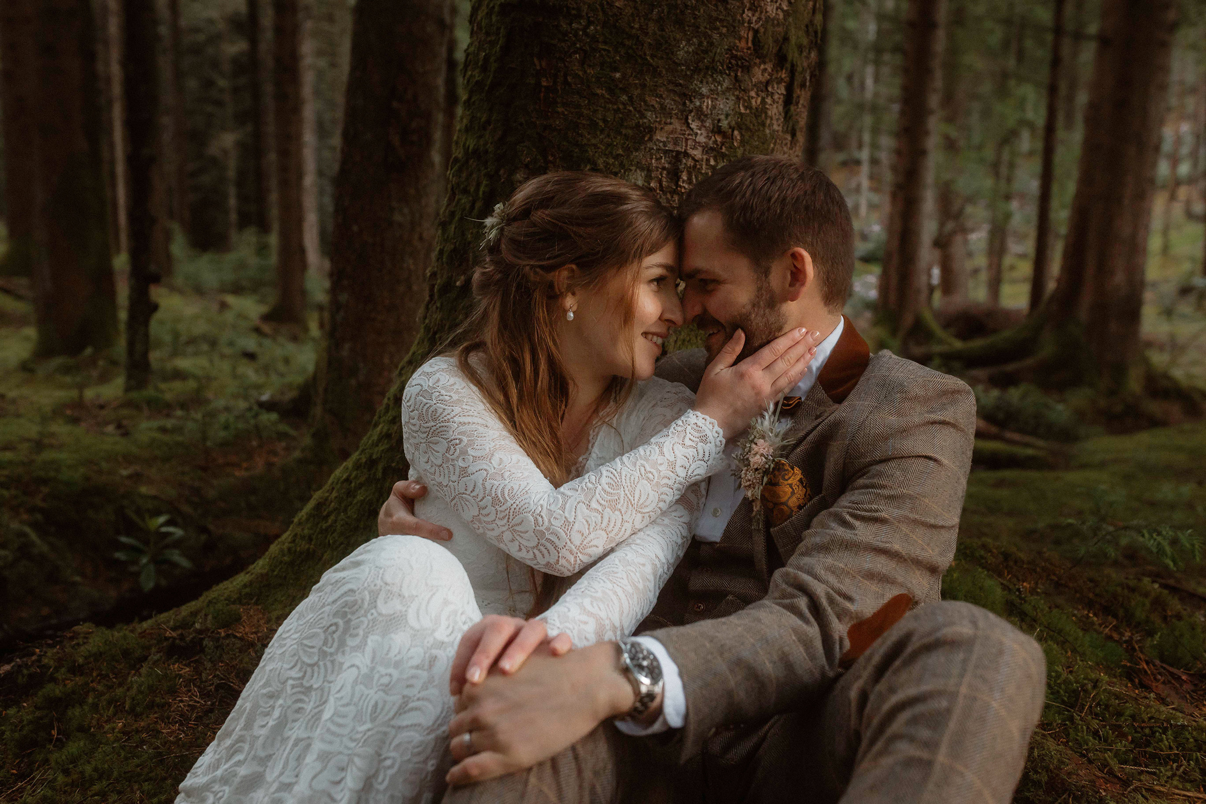 Holly and James sat on a tree after exploring the woods of Glencoe, Isle of Skye during their elopement day.