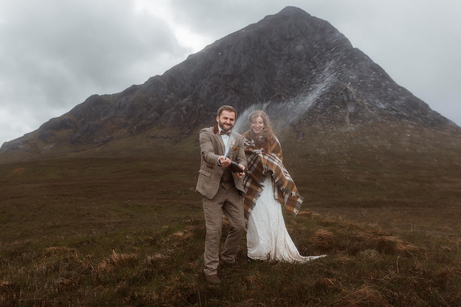 Holly and James are smiling as did a champagne spray at Buachaille Etive Mor of Glencoe after their elopement ceremony