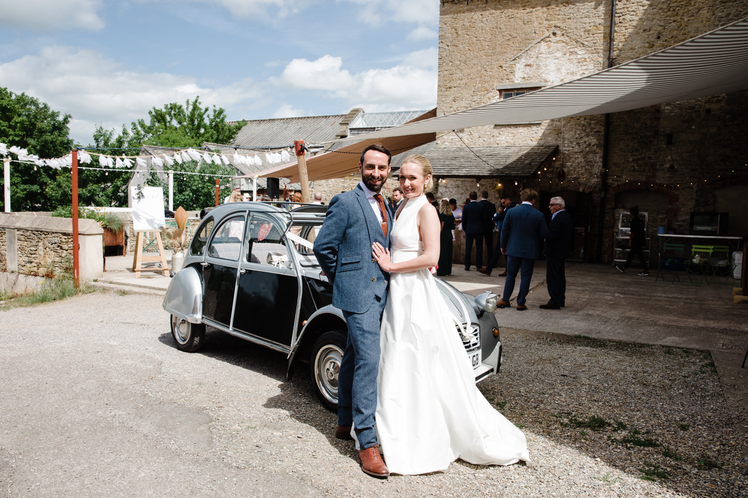 A newly married couple poses for a photograph next to  a vintage Citreön 2cv