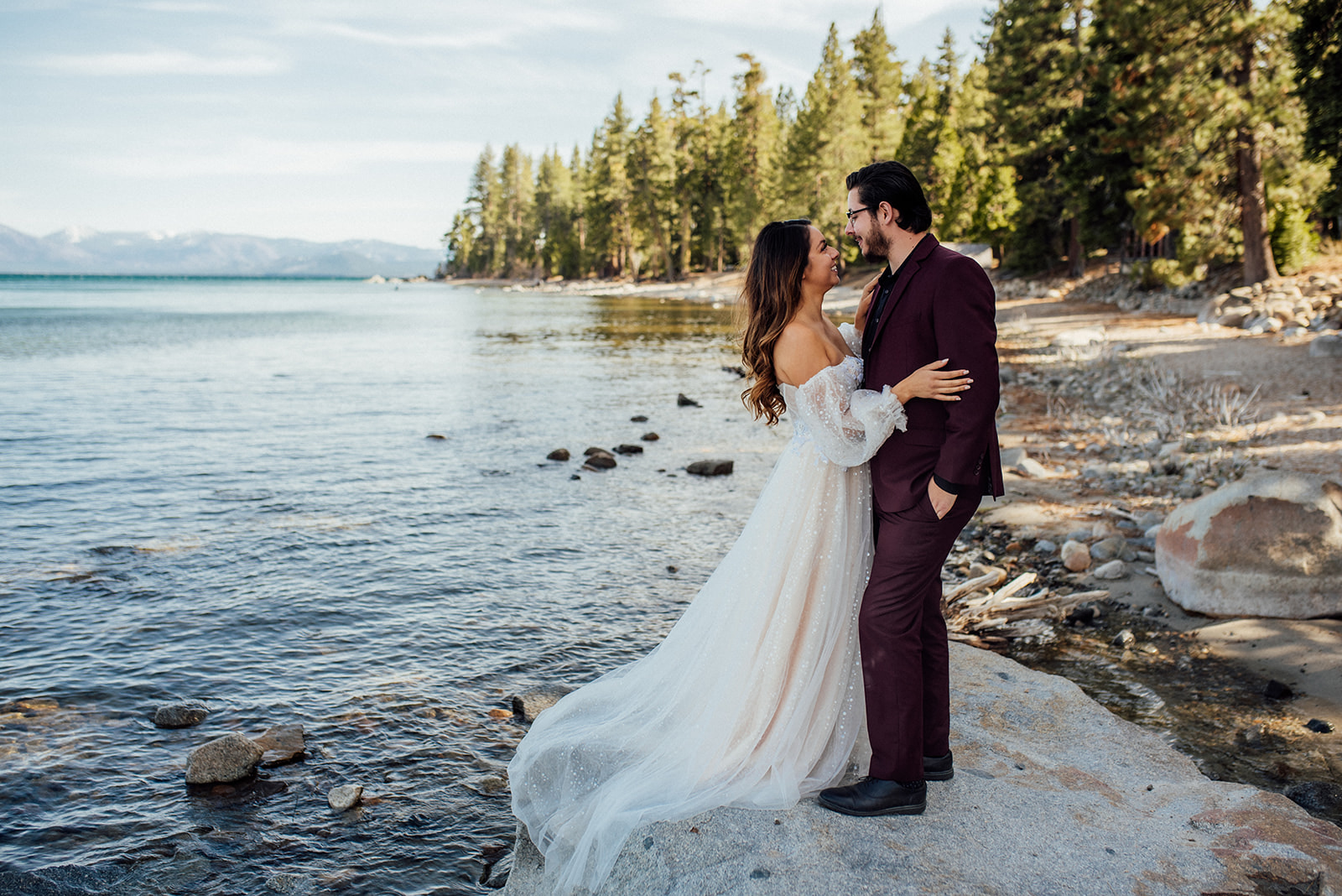 bride and groom standing on rock in front of Lake Tahoe