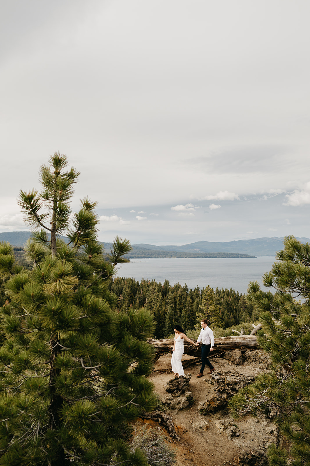 A couple walks along a lake tahoe ridge line

