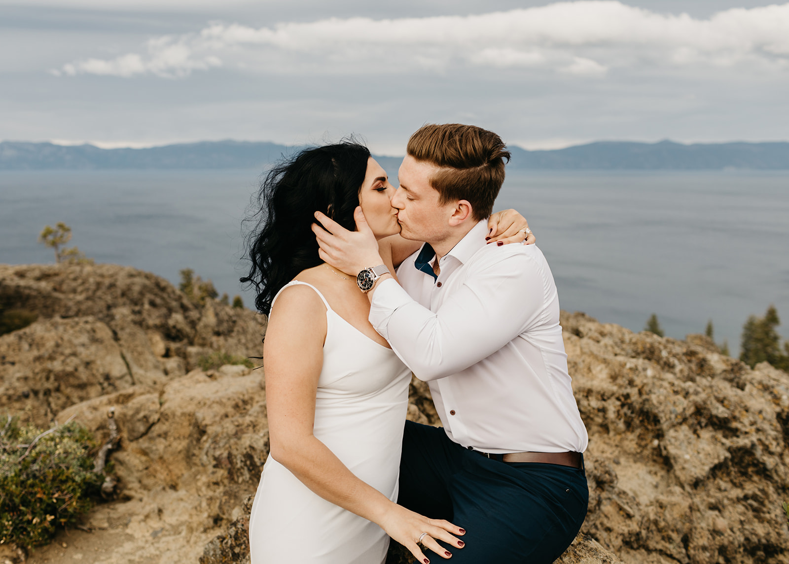 A couple shares a kiss on top of a mountain in lake tahoe