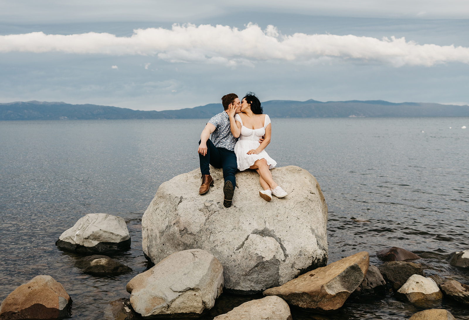 A couple sitting on a boulder in the water of lake tahoe 