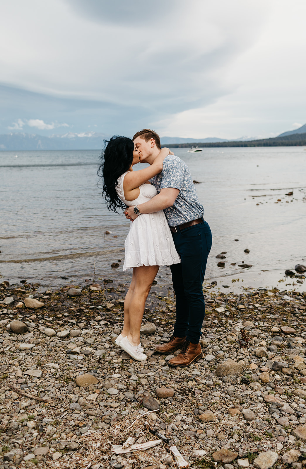 A couple goes for a dip kiss while on the rocky shore of west lake tahoe