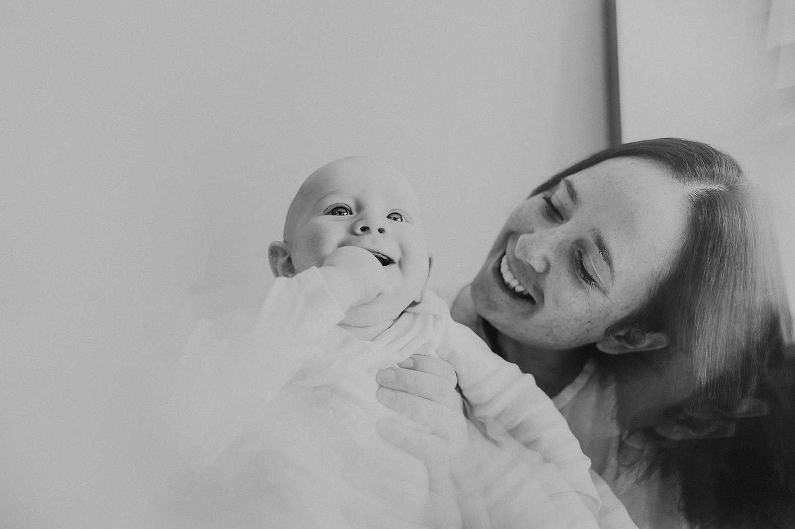 Black and white photo of baby laughing with mother
