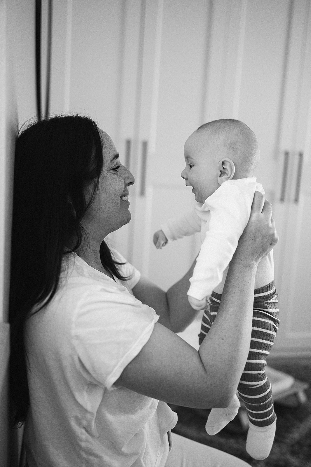 Black and white photo of mother holding up baby