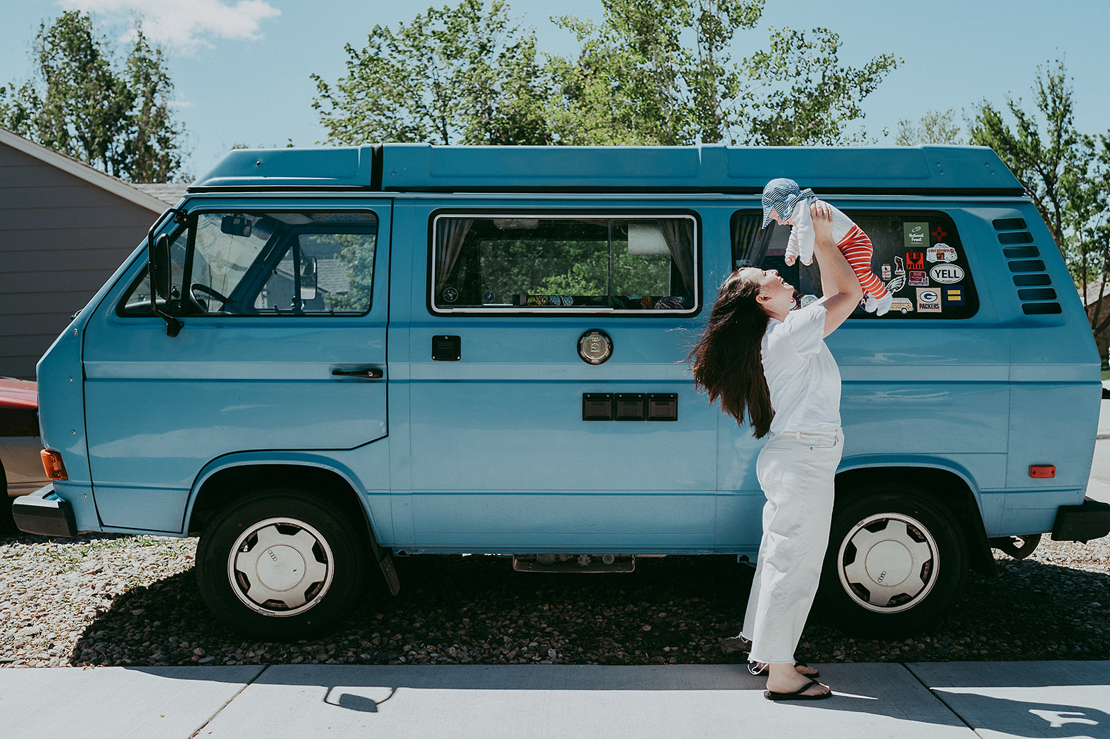 Mom holding baby up in front of VW bus