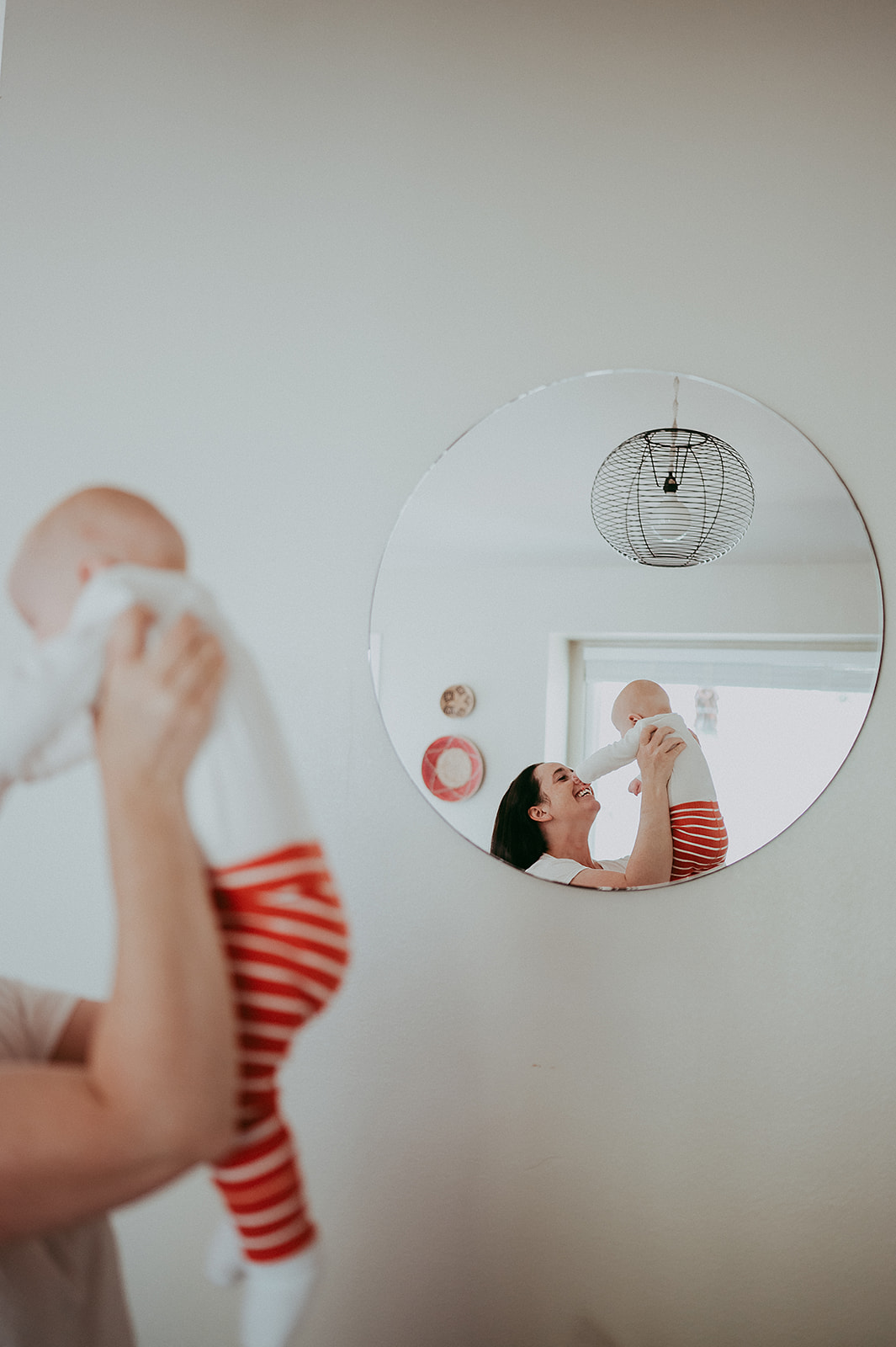Mother holding up baby in front of mirror