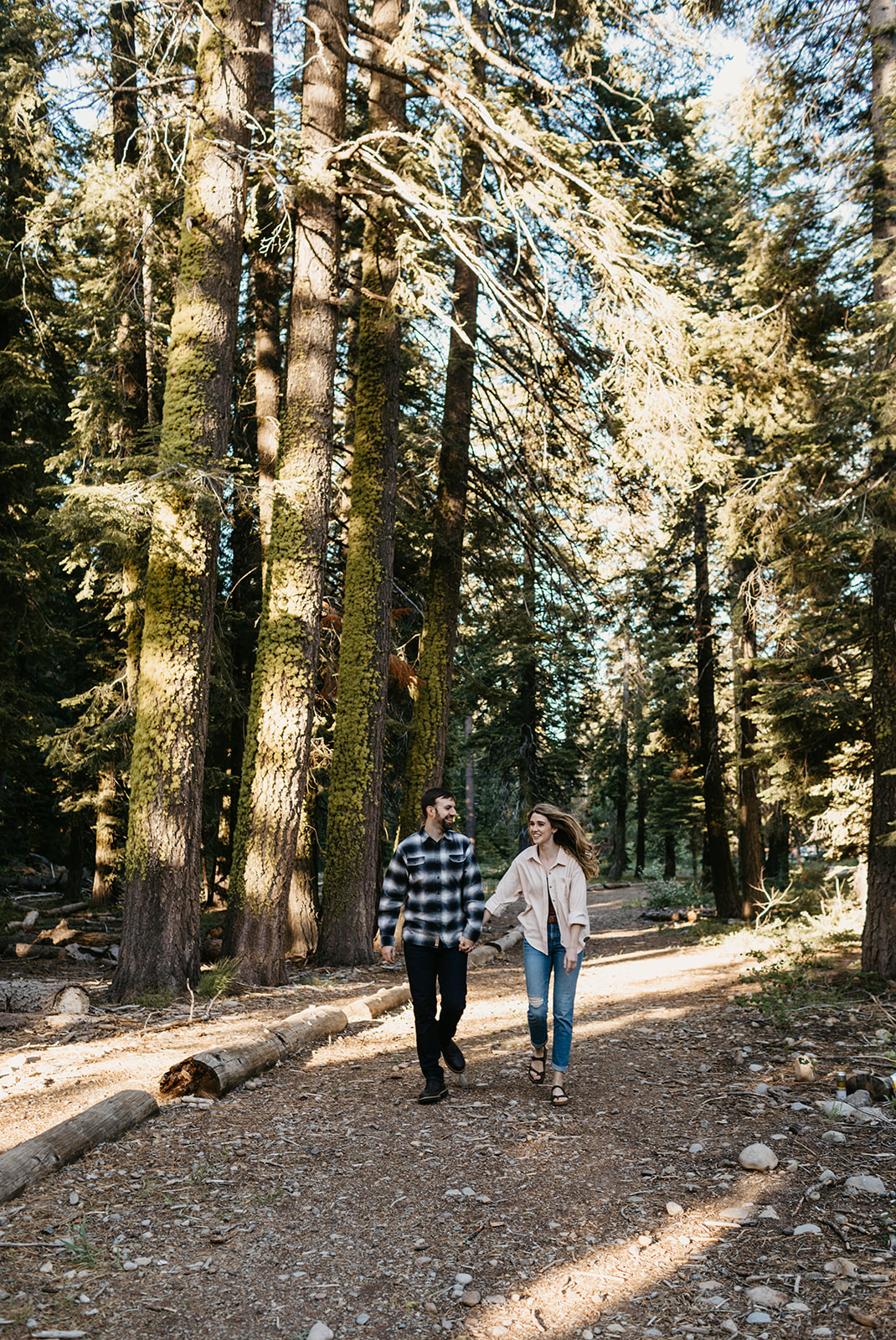 A couple walking through Tahoe National Forest, celebrating their engagement session