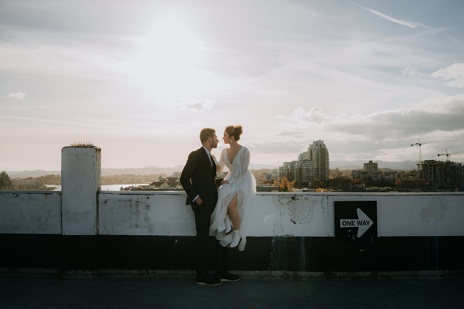 A recently married couple take in the sunset and skyline of Victoria from the rooftop of a downtown parkade
