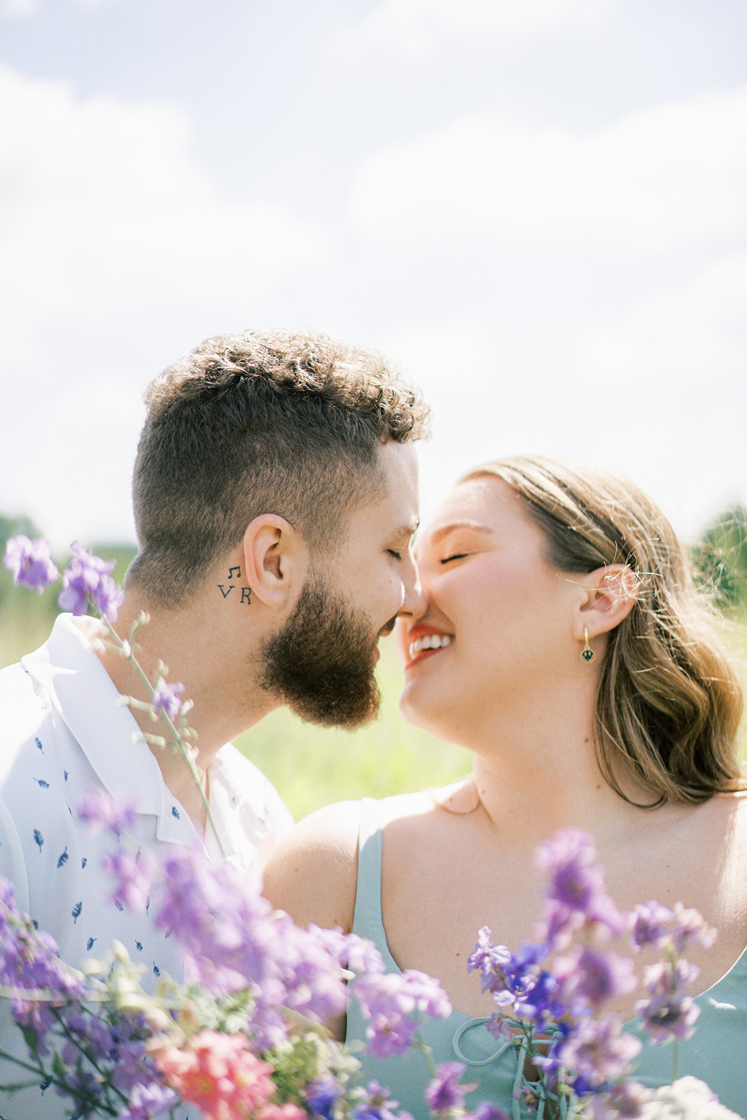A couple kisses behind a bouquet of flowers during their photography session at Wolf Thicket Farm