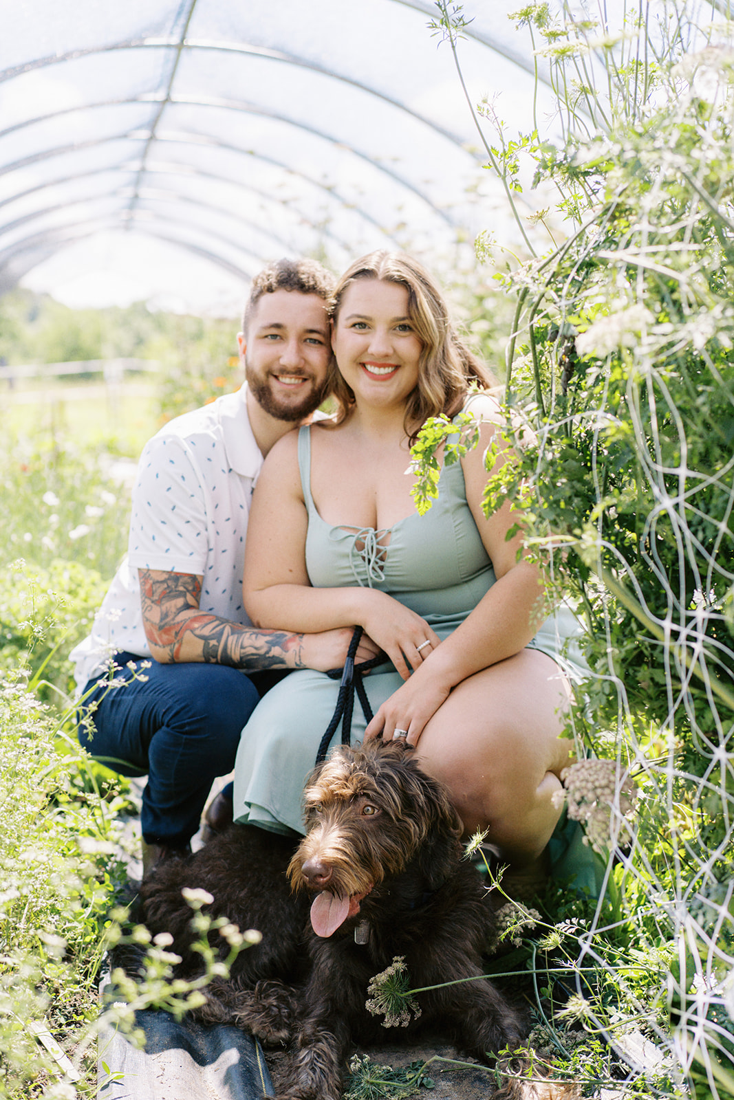 The couples smiles with their dog amongst the fresh flowers at Wolf Thicket Farm in North Alabama