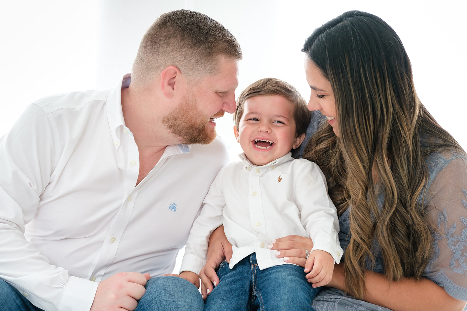Little boy laughs with his parents in a light and airy Tampa studio session