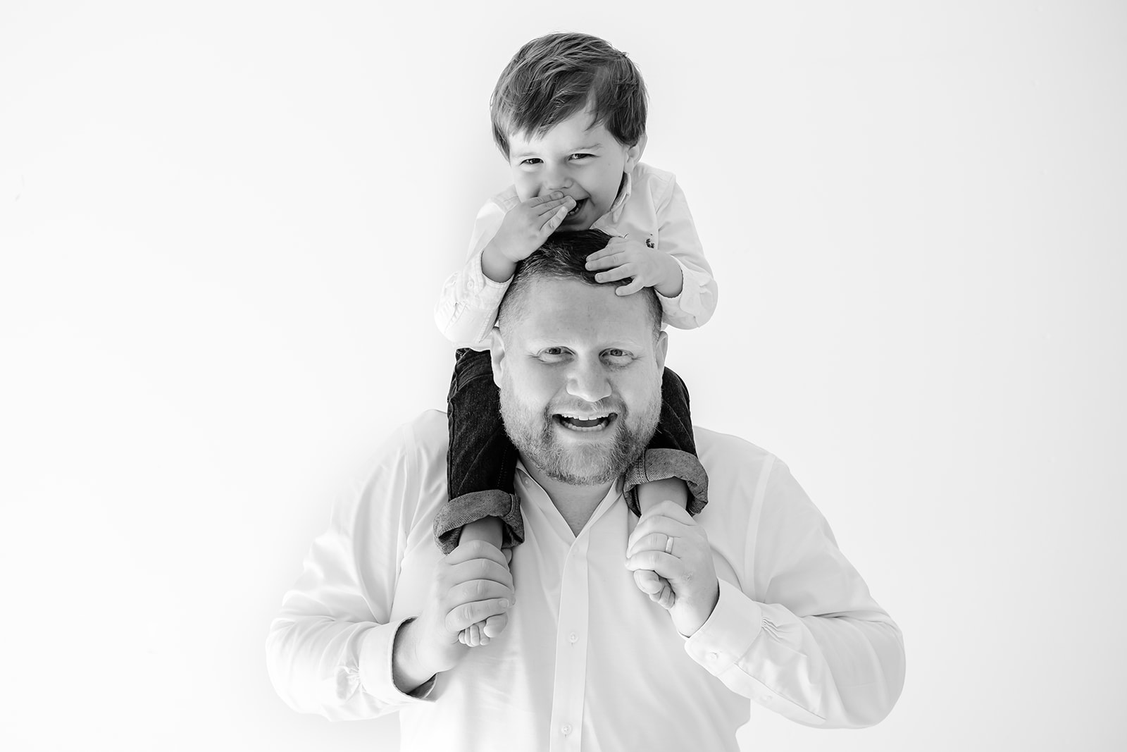 Little boy sits on dad's shoulders and laughs during a Tampa family photography session