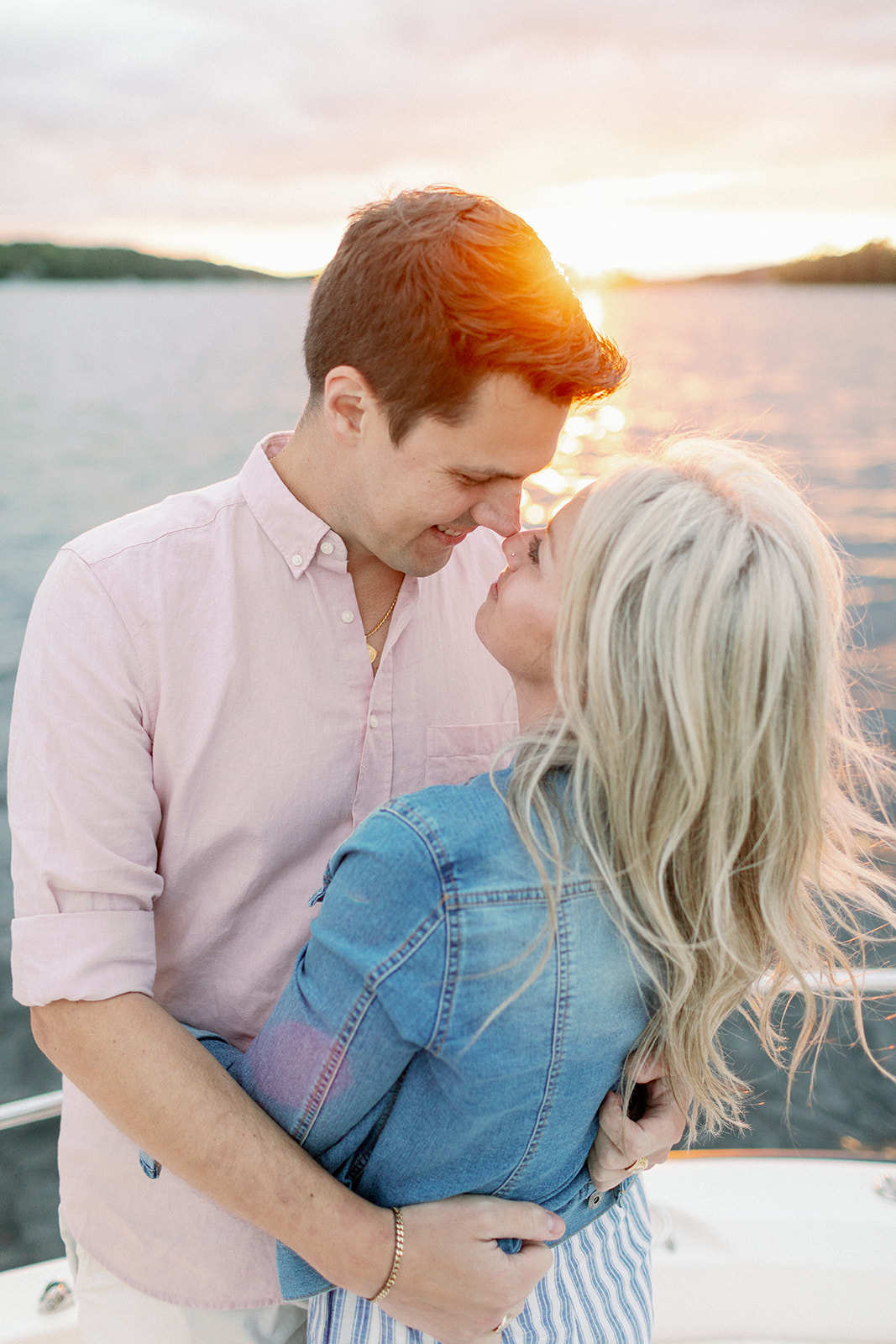 Couple embrances during their engagement shoot at sunset during a pastel pink sunset