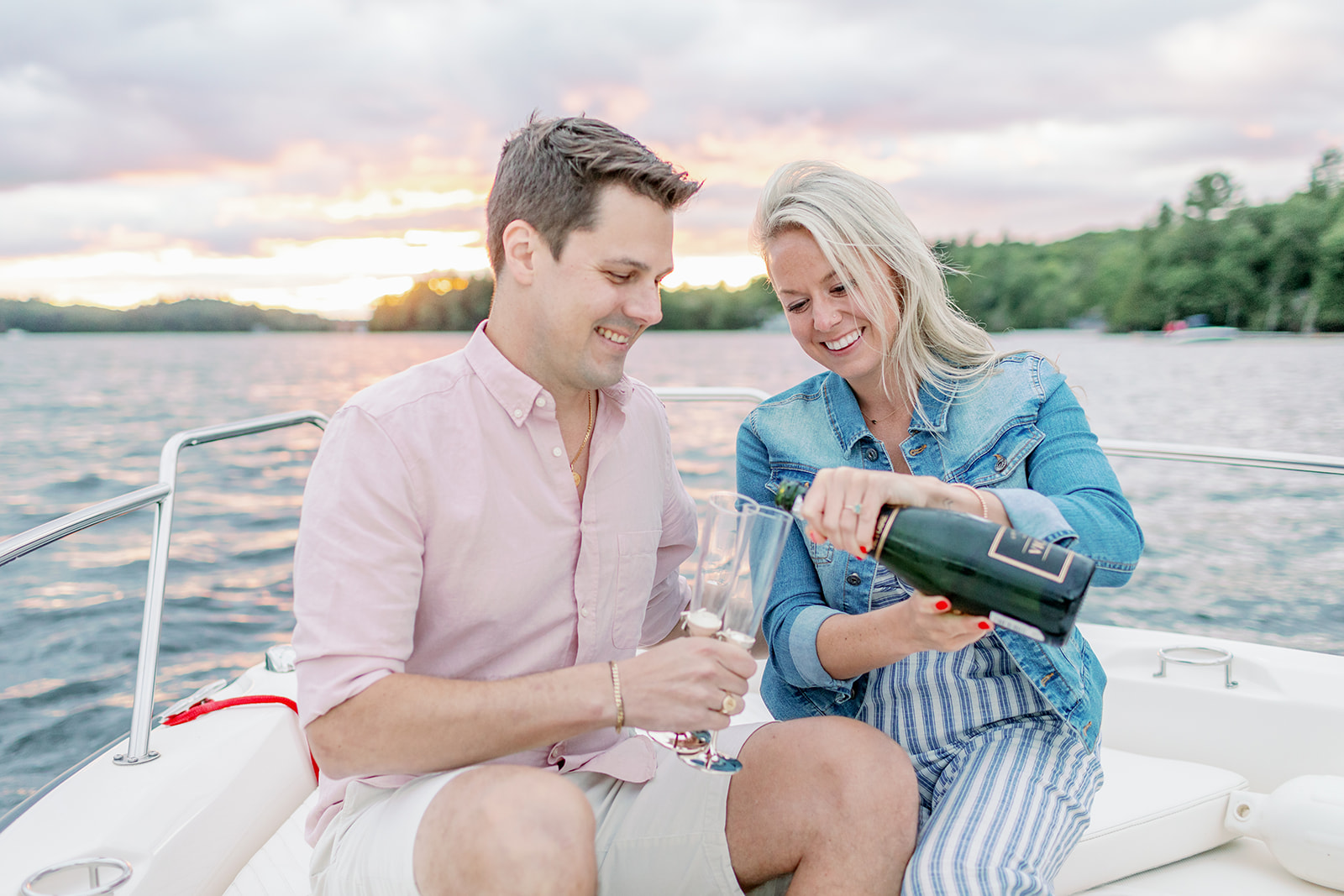 Couple pours champagne on boat during sunset engagement photoshoot 