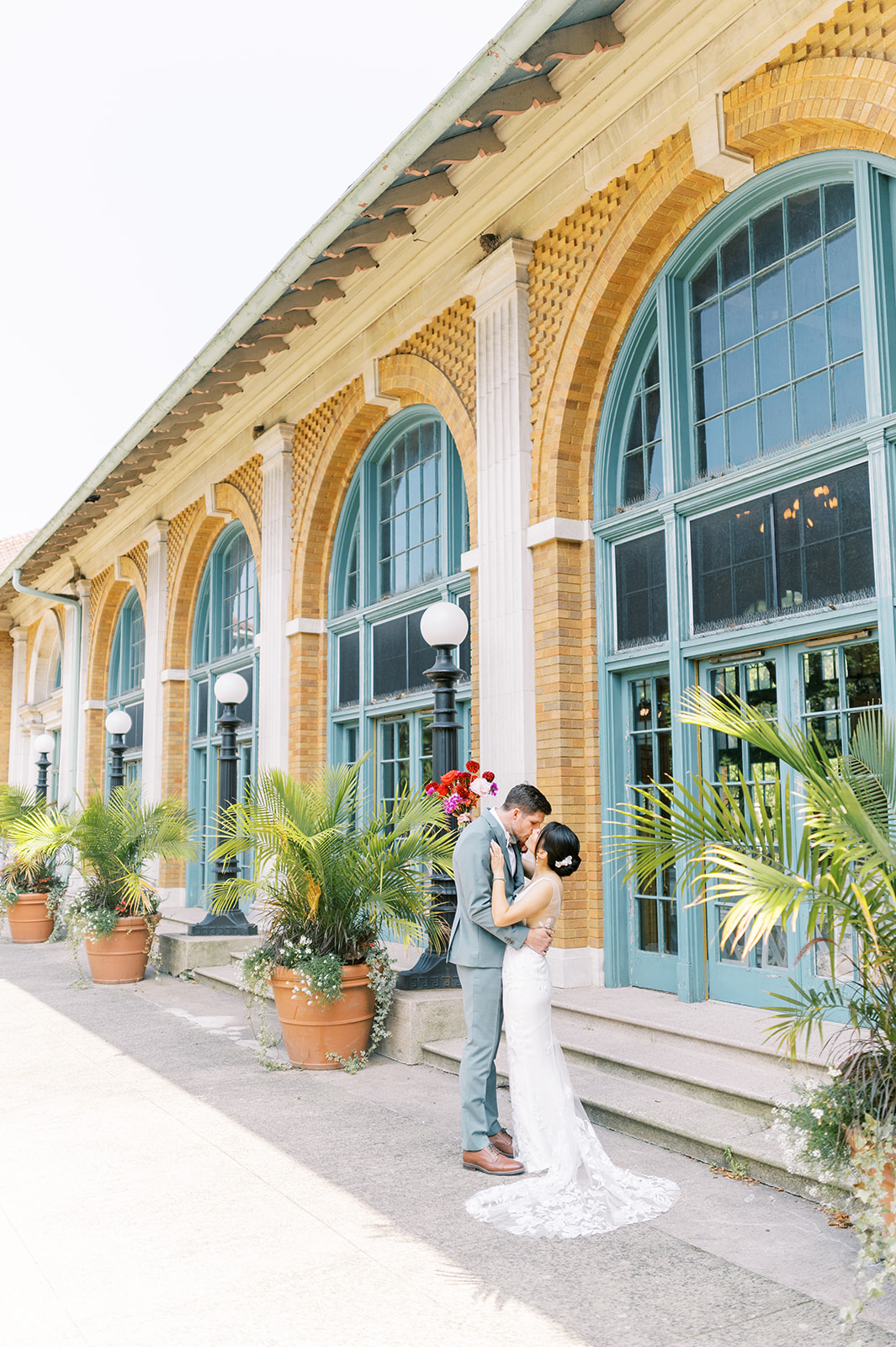 bride and groom kissing on summer day in front of columbus park refectory