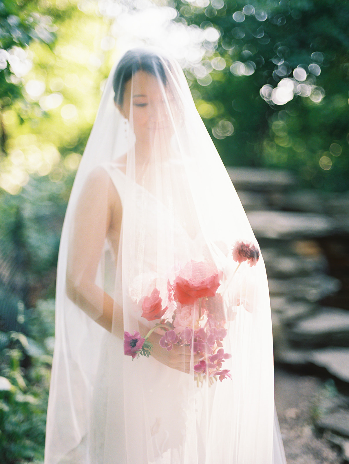 bride with modern red bouquet and veil draped over her