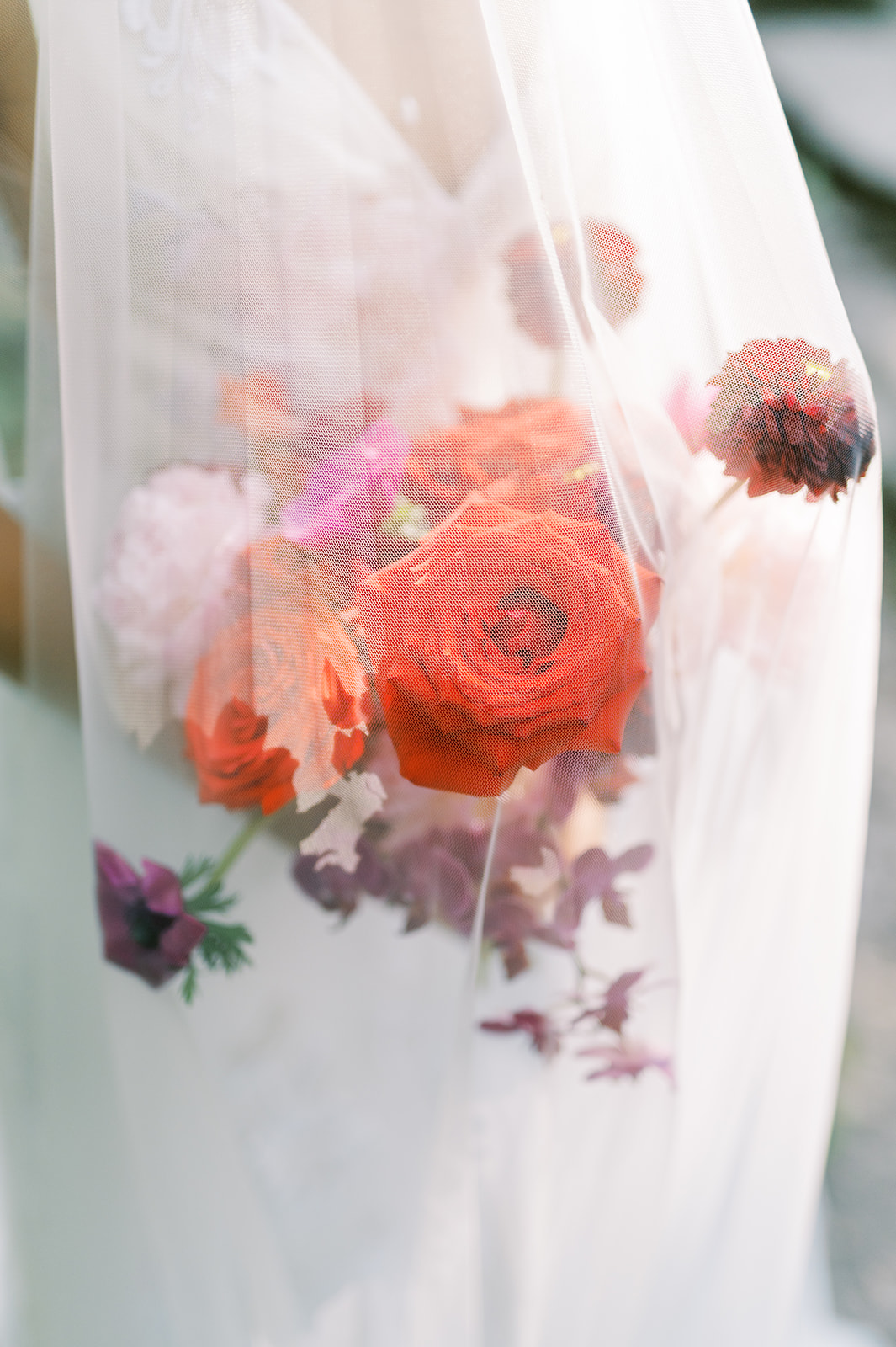 modern bright red and fuchsia bridal bouquet under veil