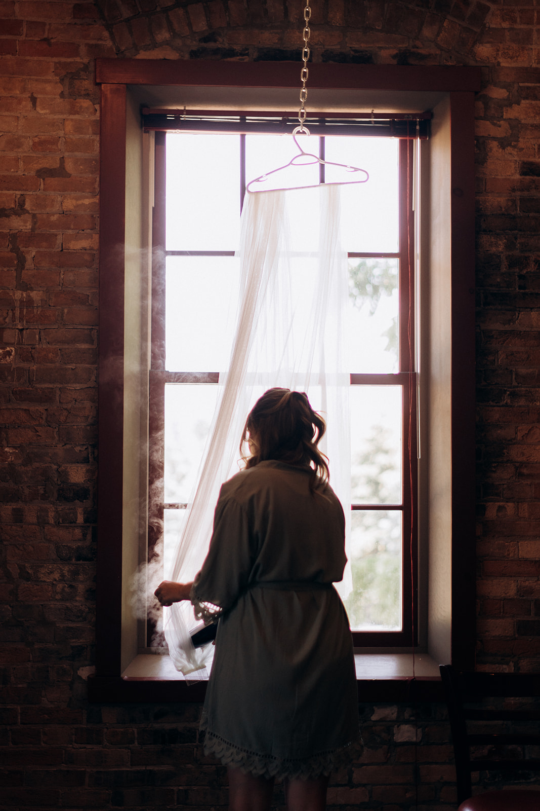 Bridesmaids steaming a veil by the window at the Mill