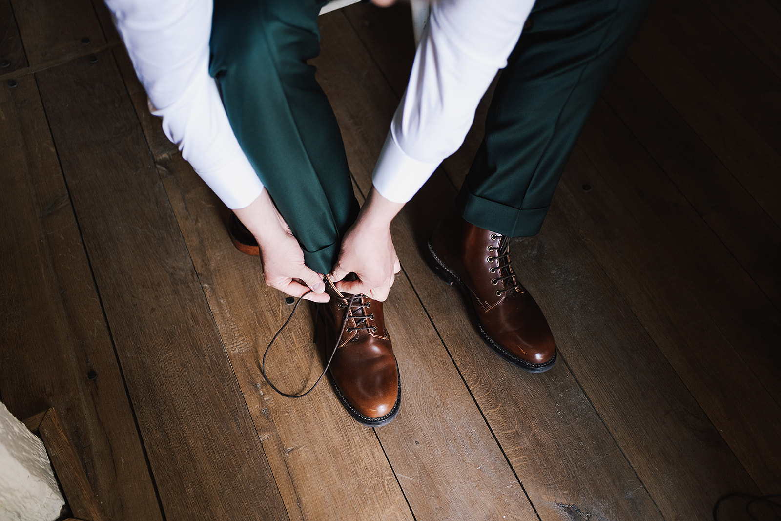 Groom tying up laces in his Grenson books