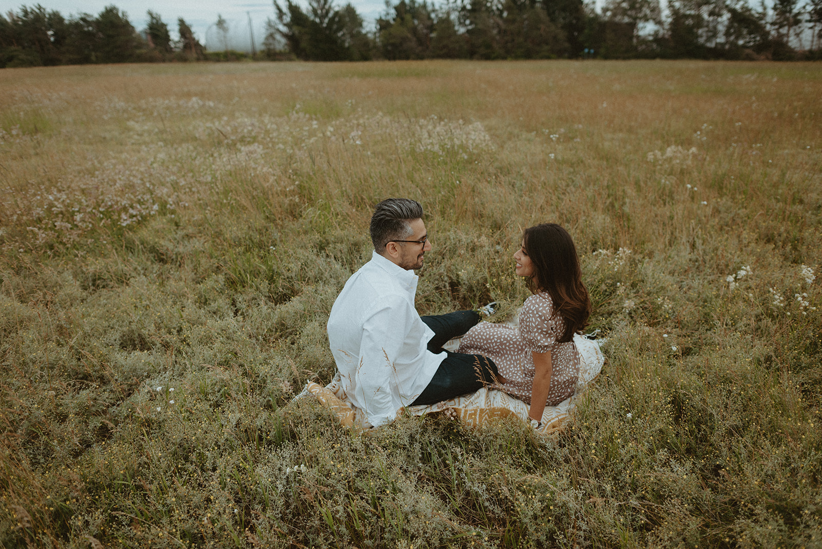 couple sitting in tall wildflower field