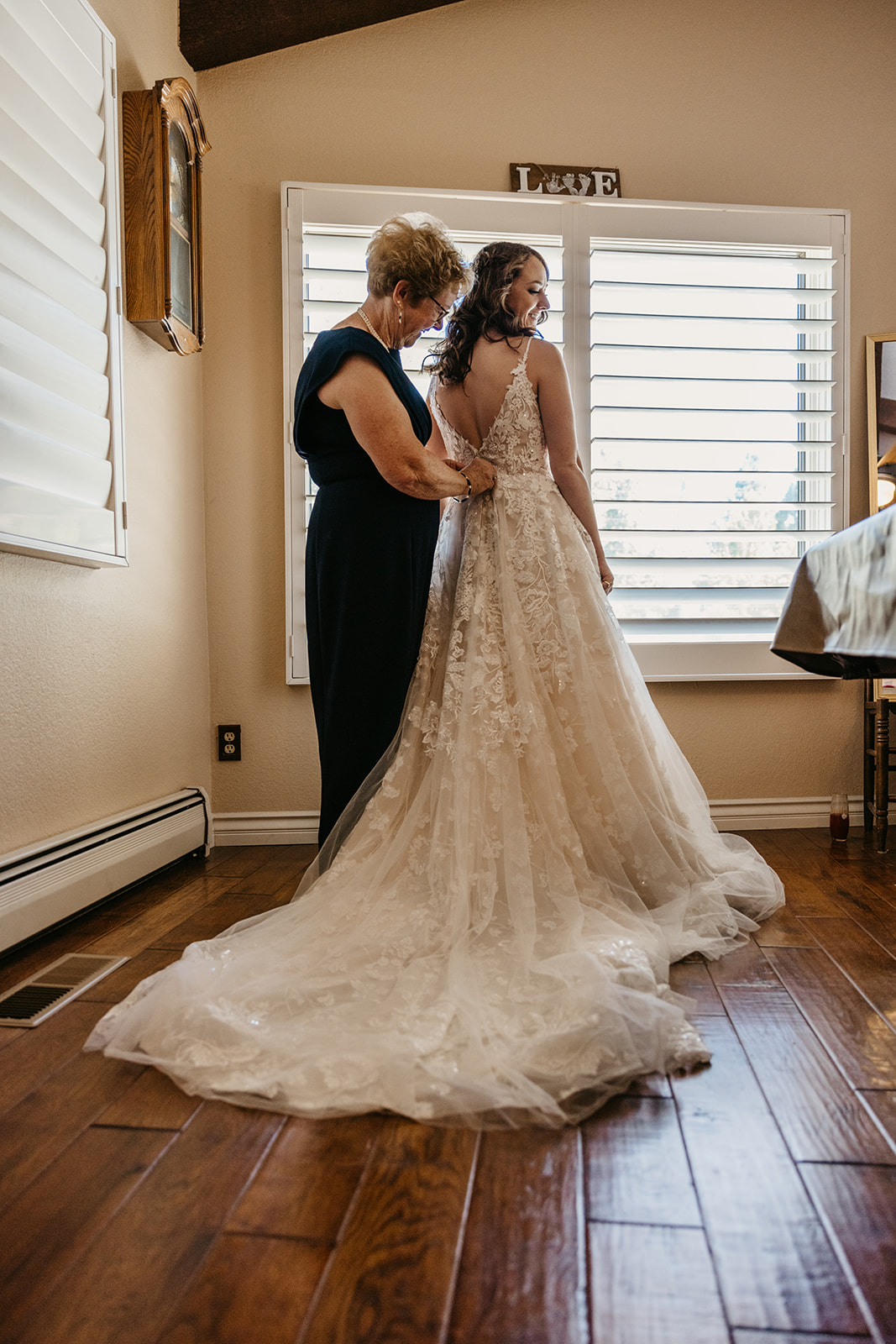 Bride's mom helps button up her wedding dress