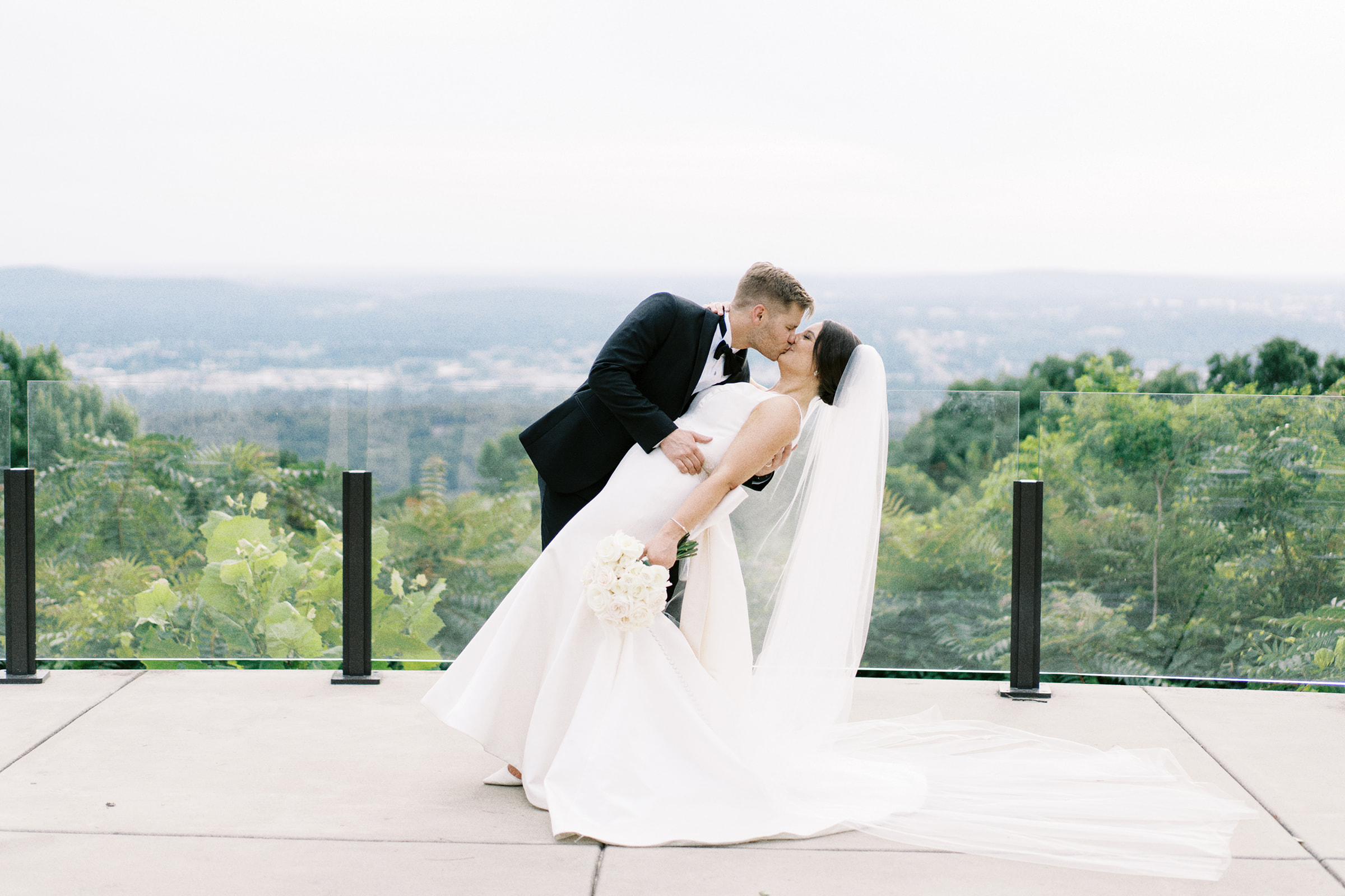 A bride and groom dip and kiss on the bluff at Burritt on the Mountain in Huntsville, Alabama