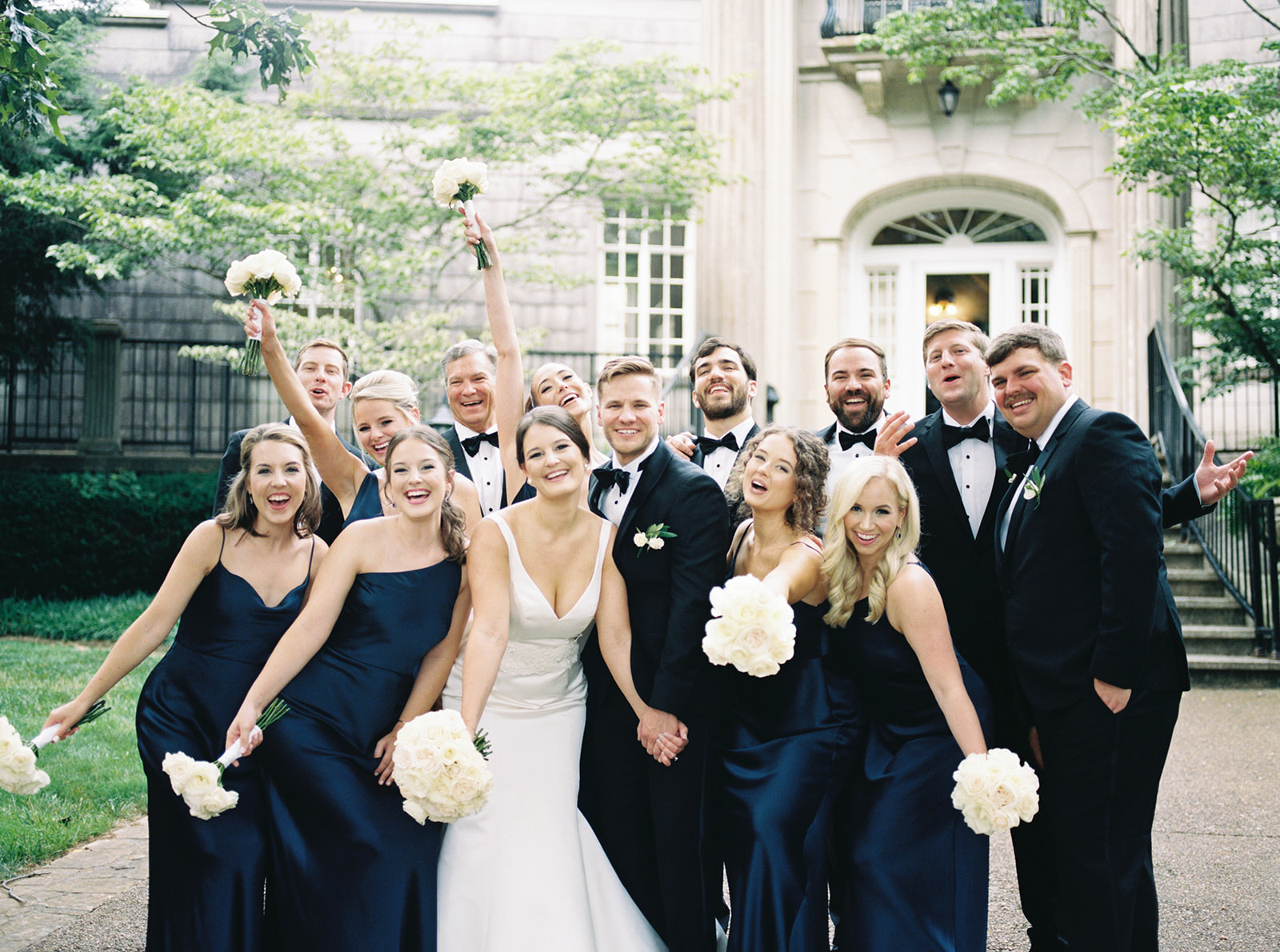 The wedding party poses excitedly for a photo in front of the mansion at Burritt on the Mountain