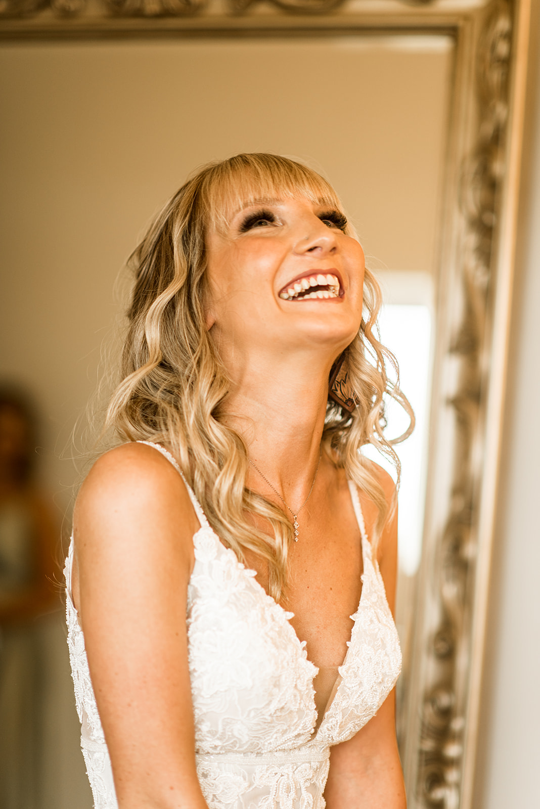 bride laughs while getting dressed on her wedding day
