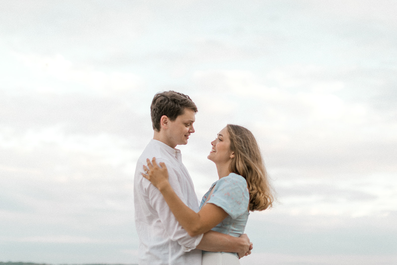 Couple embraces during engagement session on the beach in Toronto, Ontario