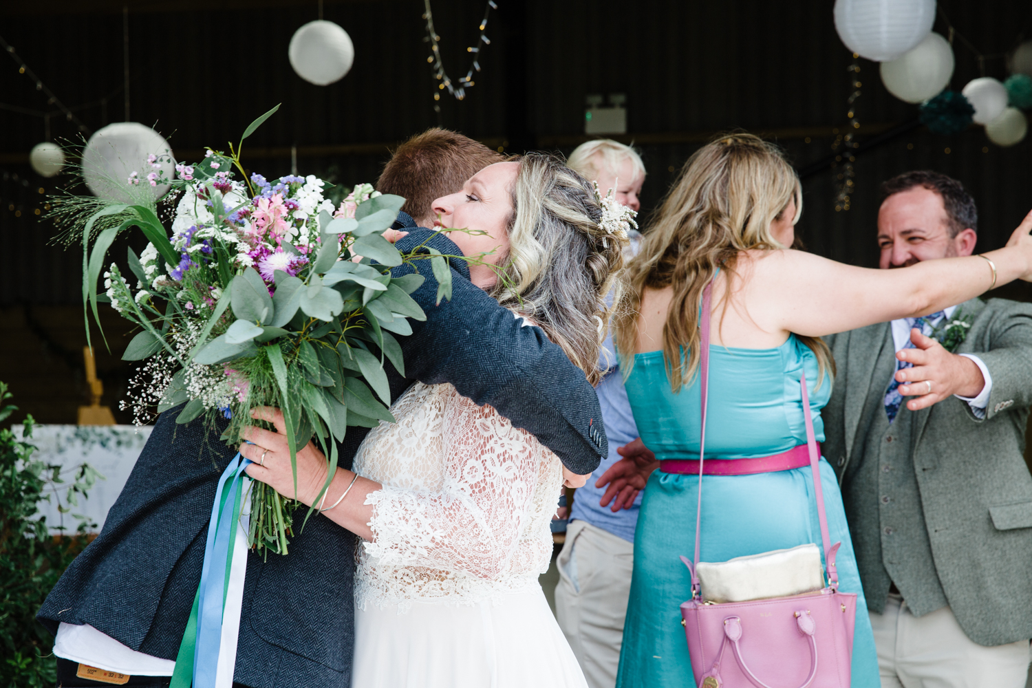 bride holding flowers hugs a wedding guest after getting married