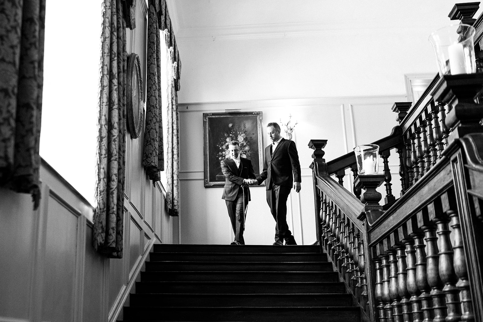 Groom and groomsmen shaking hands and walking down the staircase. black and white image