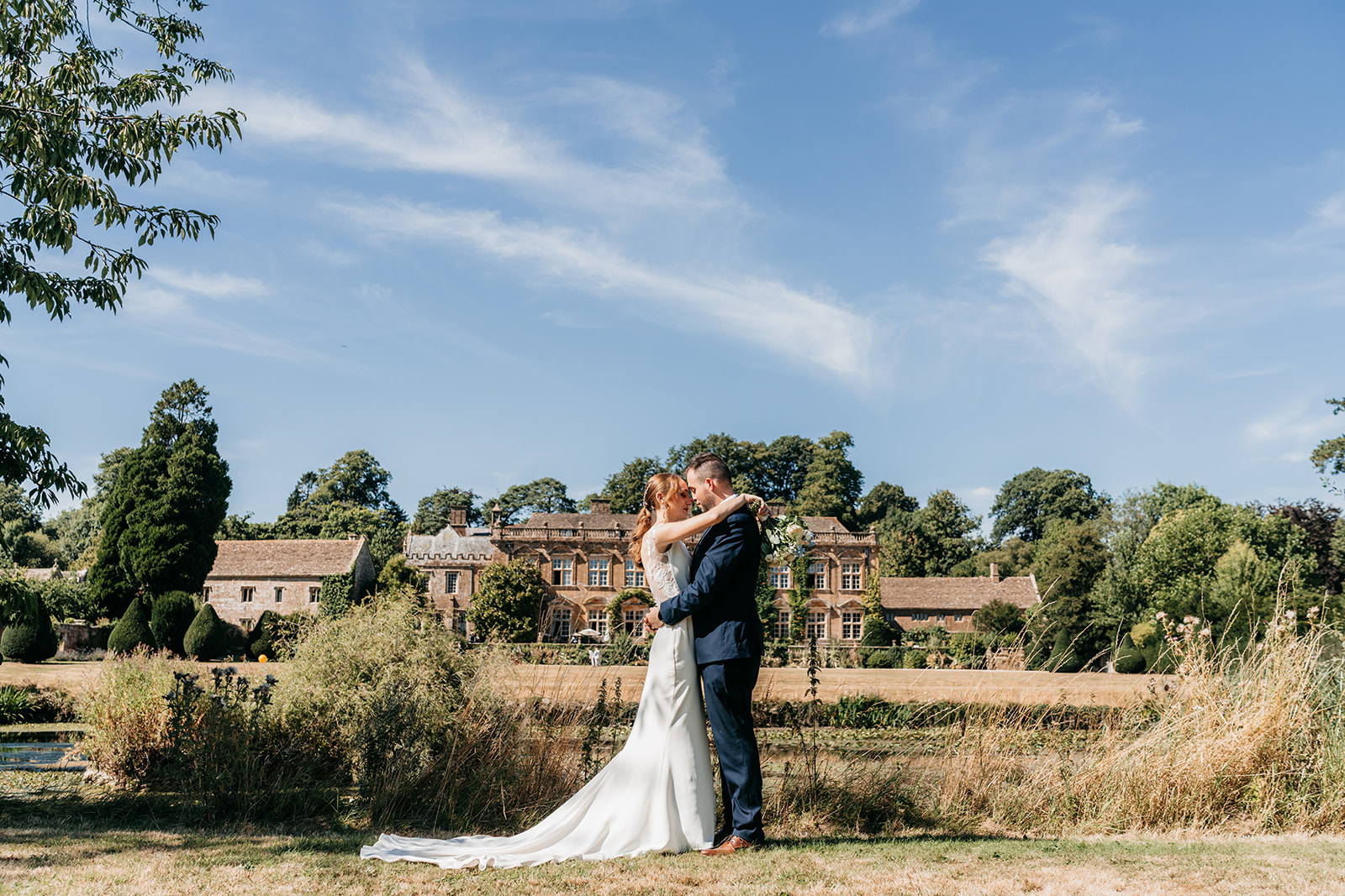The bride and groom with their Somerset wedding venue in the background 