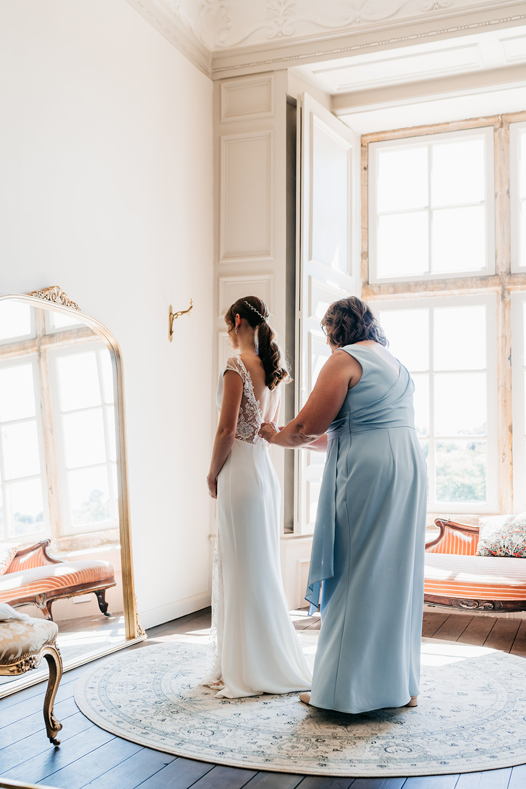 The mother of the bride helping her daughter into her wedding dress