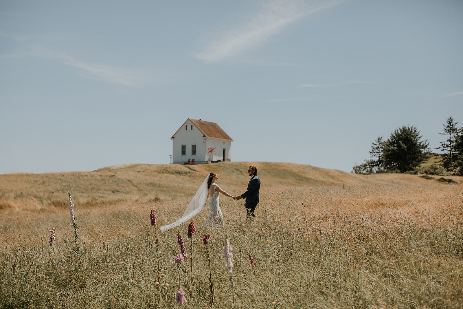 bride and groom walking through a wildflower field on Saturna Island 