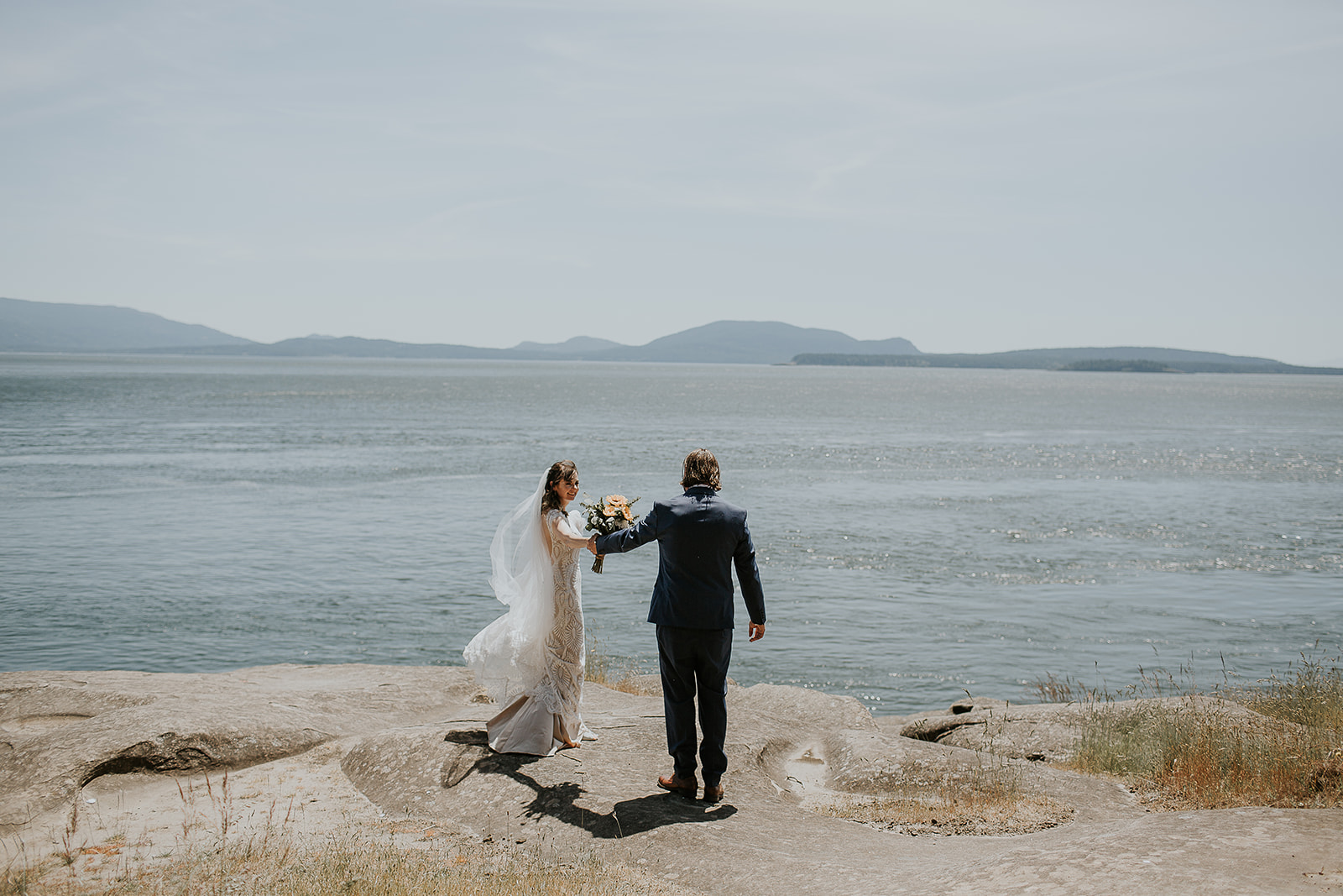 a groom admiring his bride overlooking the ocean and mountains on Saturna Island