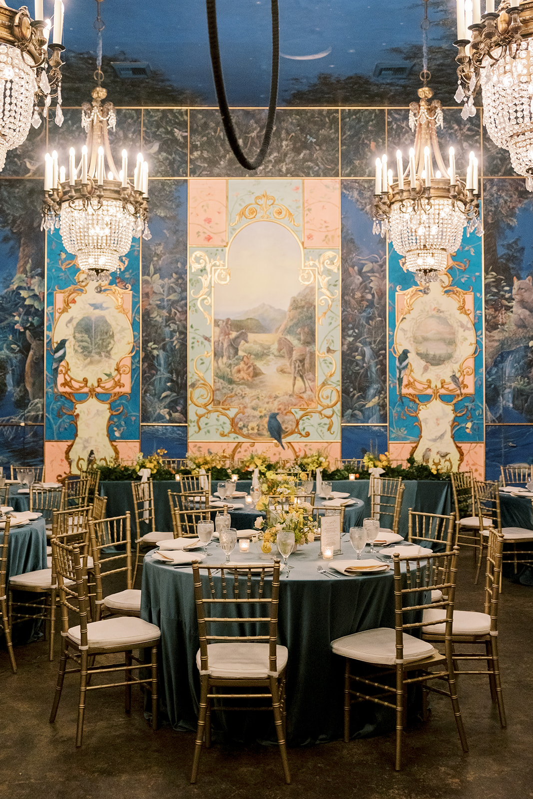 The Ruins wedding reception with crystal chandeliers and round tables with blue tablecloths 