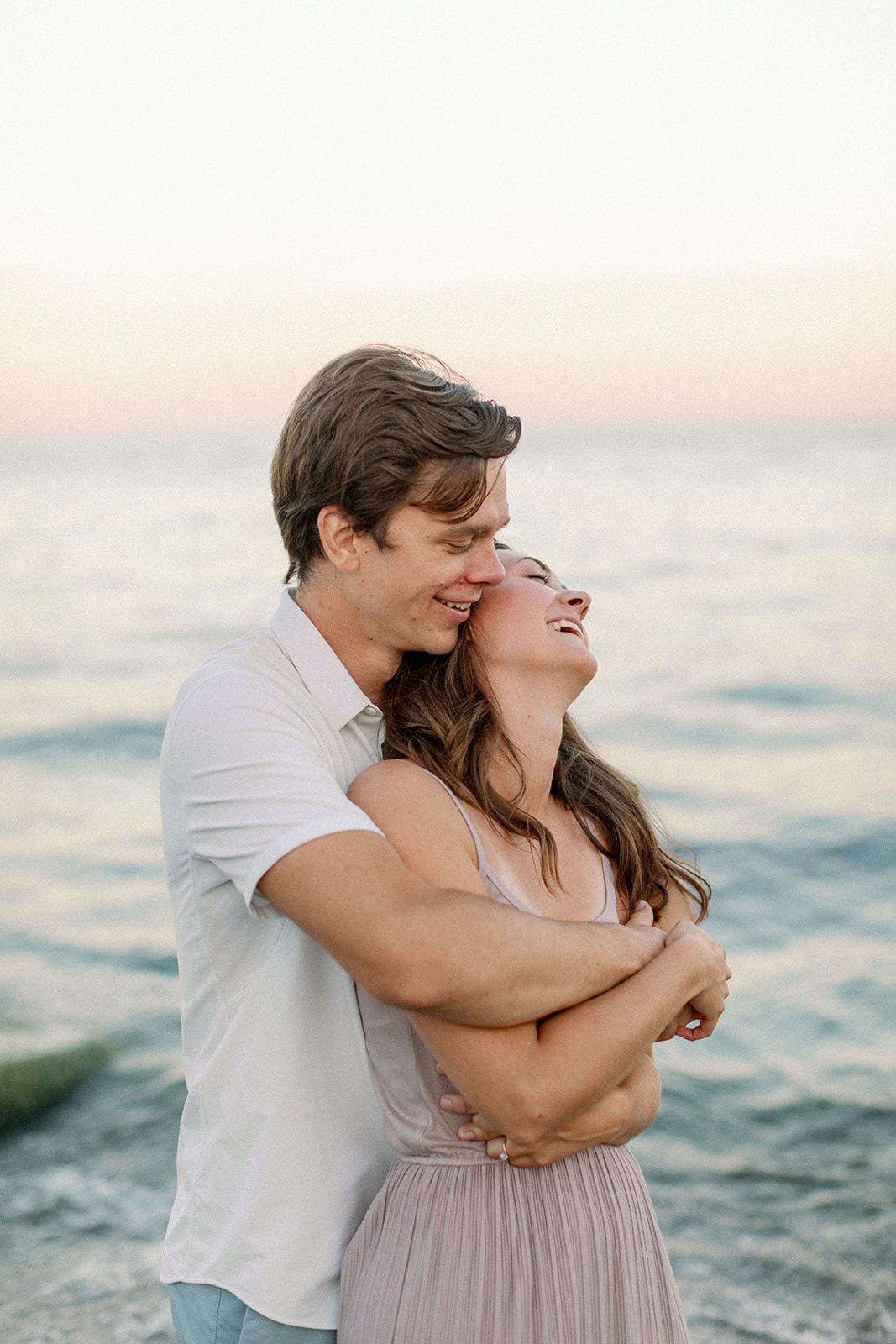Couple lovingly embraces during sunset at their engagement session