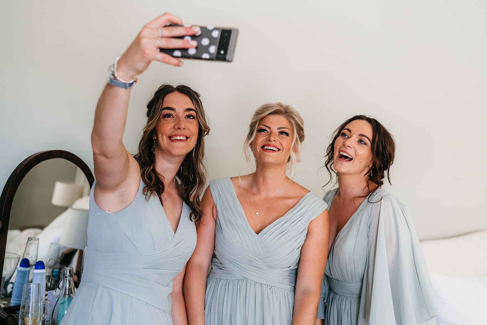 Bridesmaids taking selfies during bridal prep 