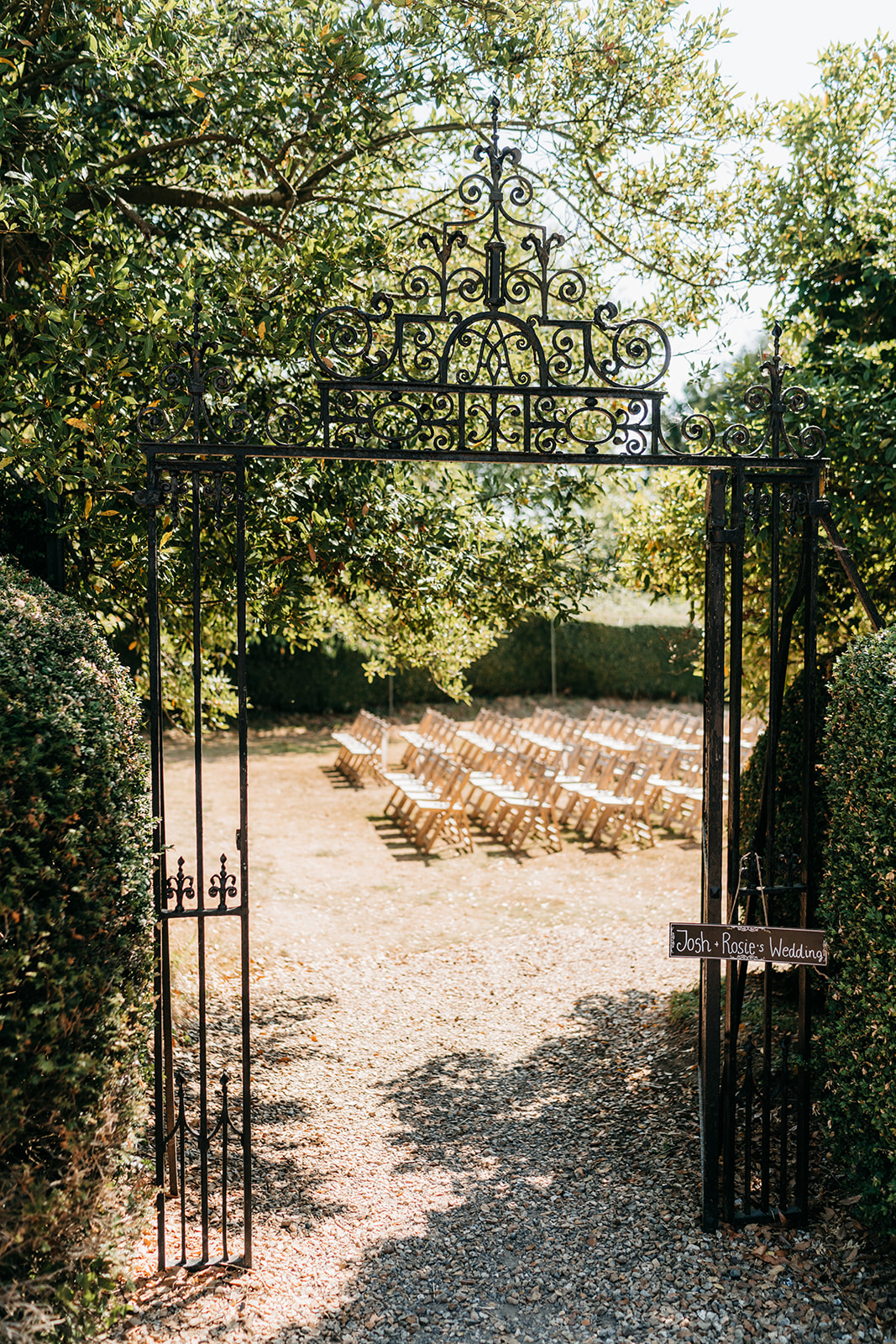 A glimpse of the outdoor wedding ceremony through iron gates and trees