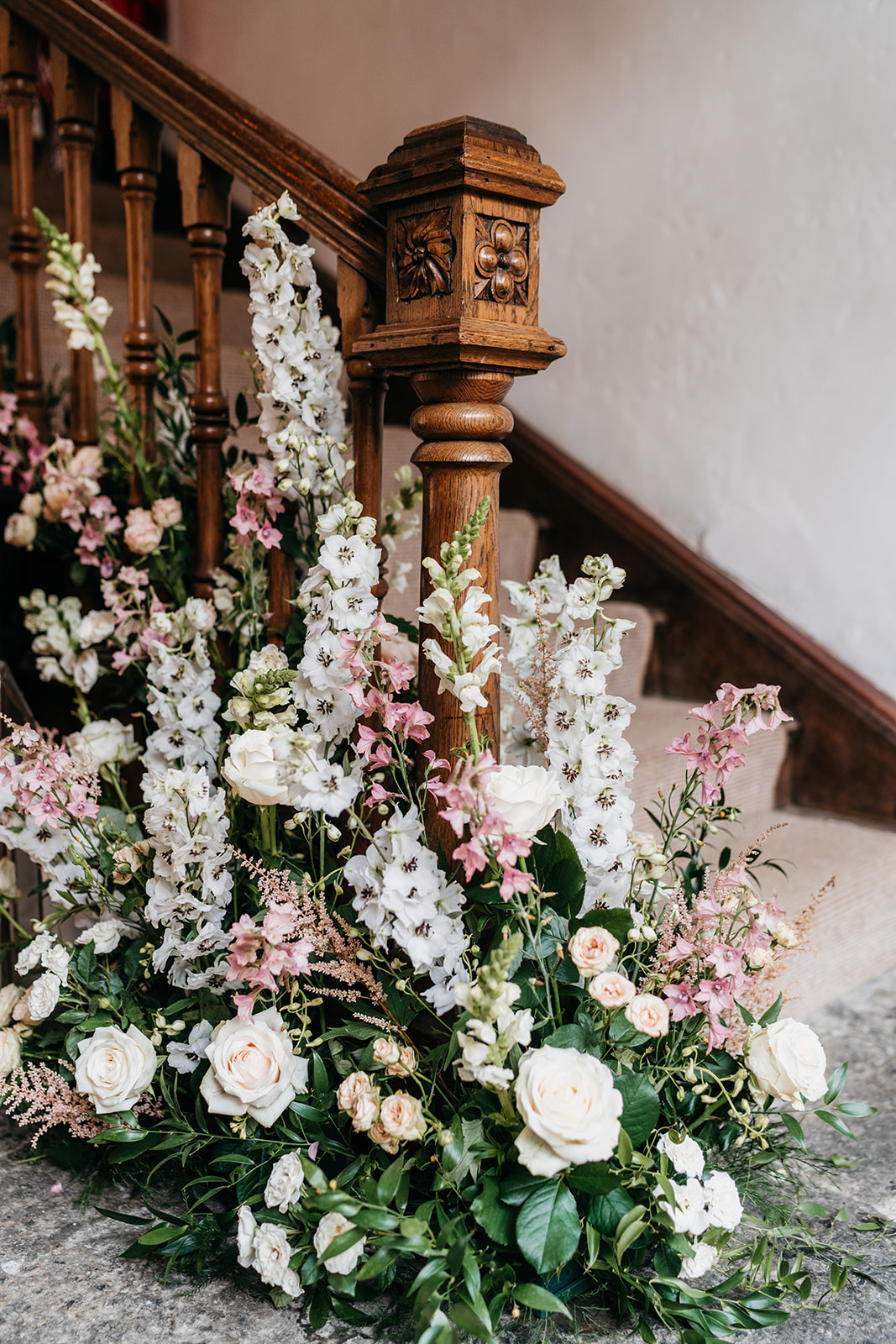 Stunning wedding flowers around the bottom of the wooden staircase by Alexandra Sylvester flowers