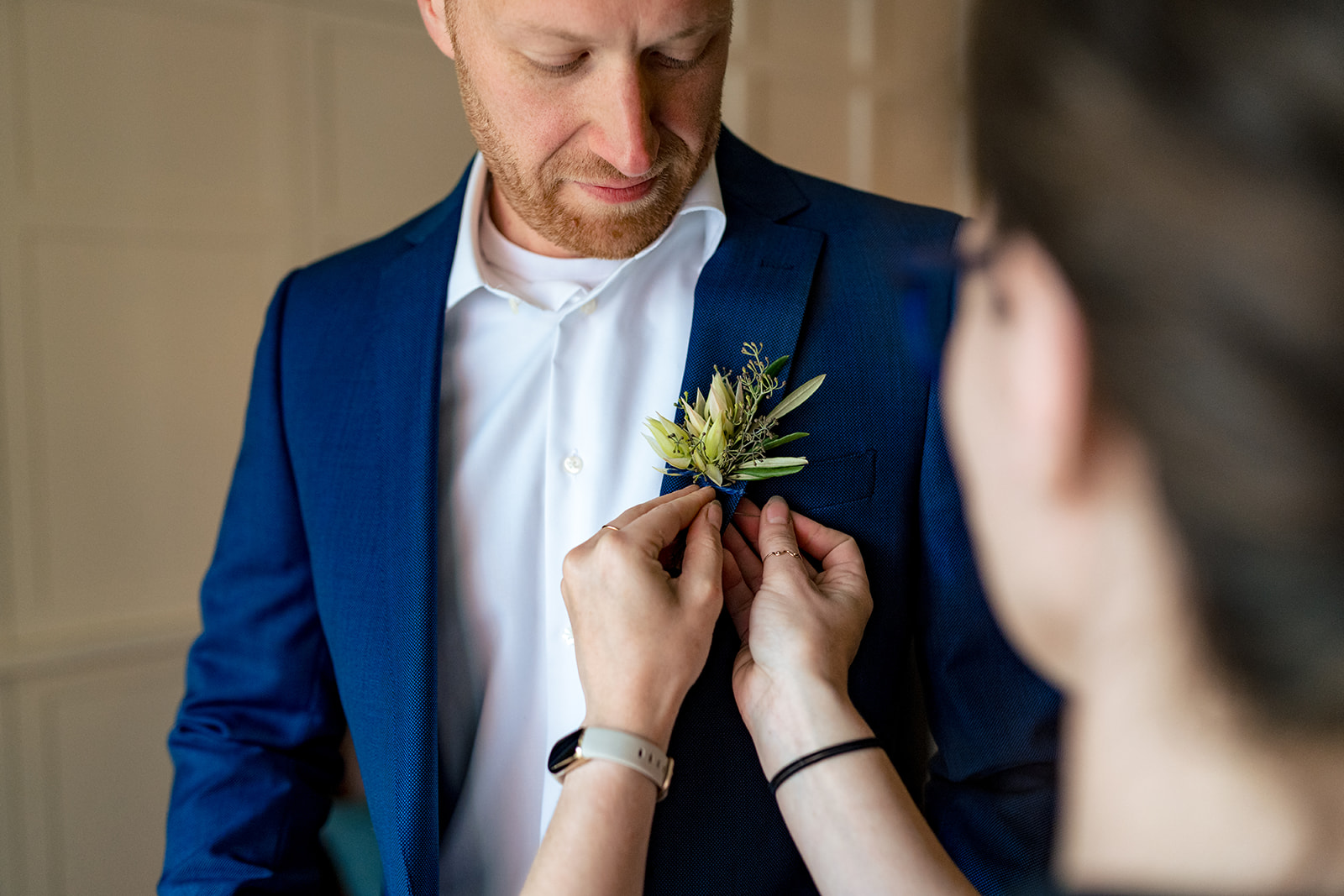 groom getting boutonniere pinned on jacket