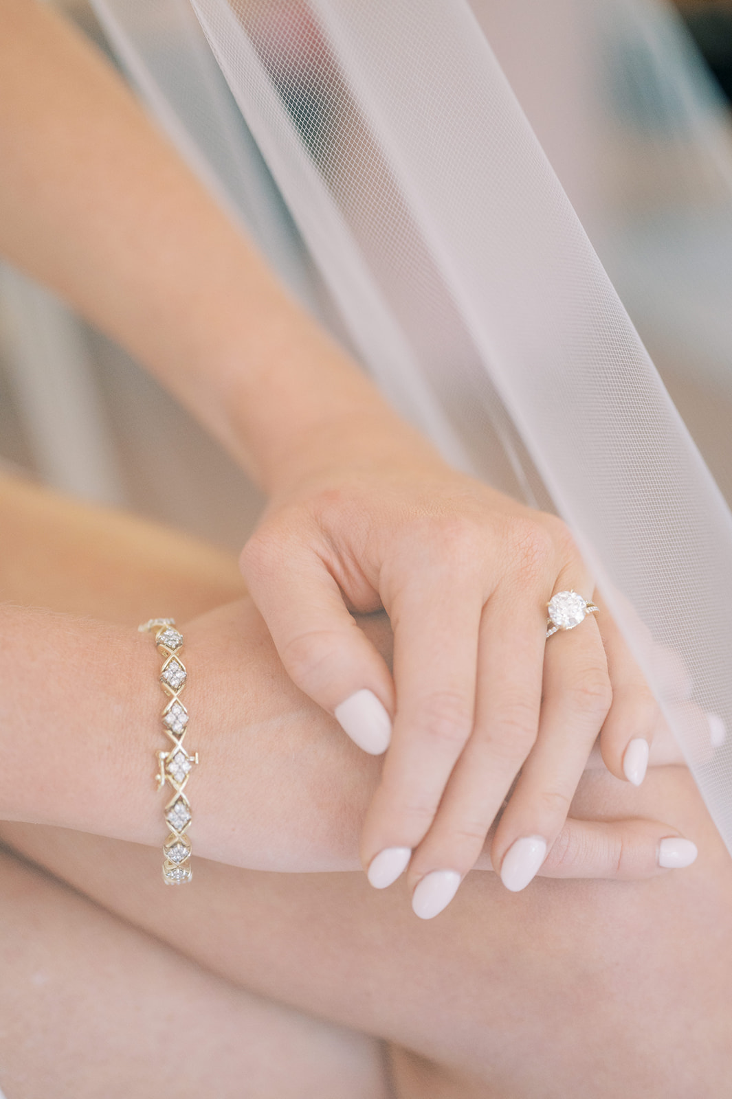 close photo of hands with engagement ring, bracelet, and pretty nails