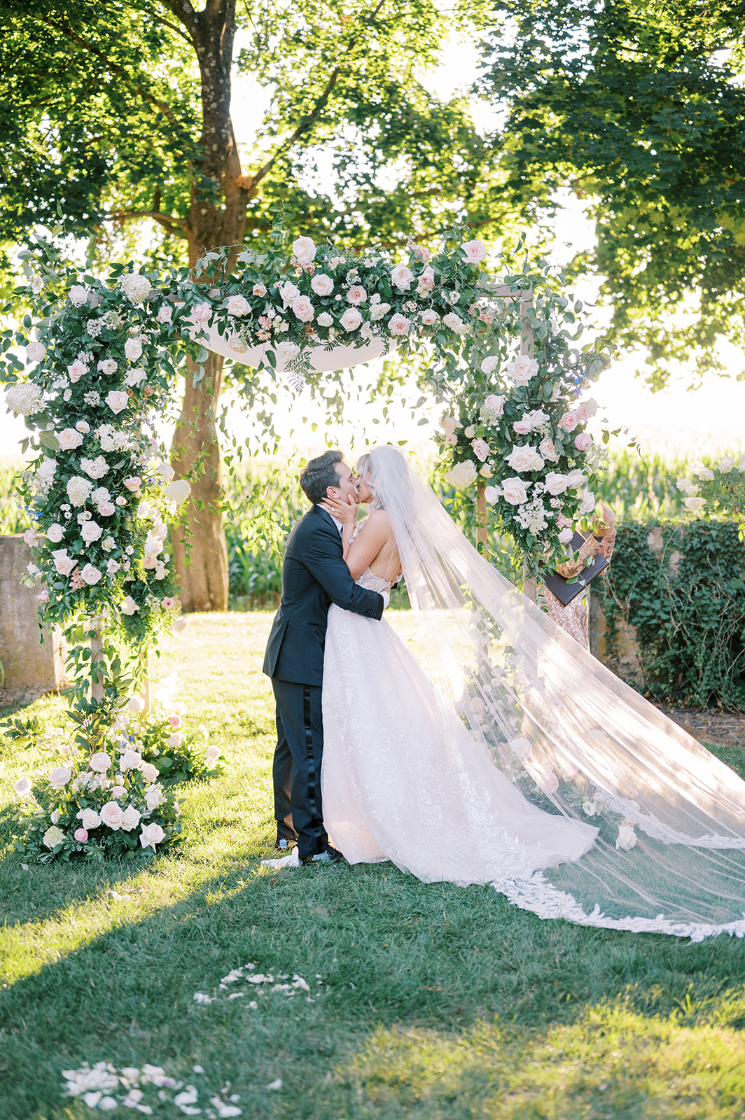 romantic kiss in the sun under ram floral arbor 
