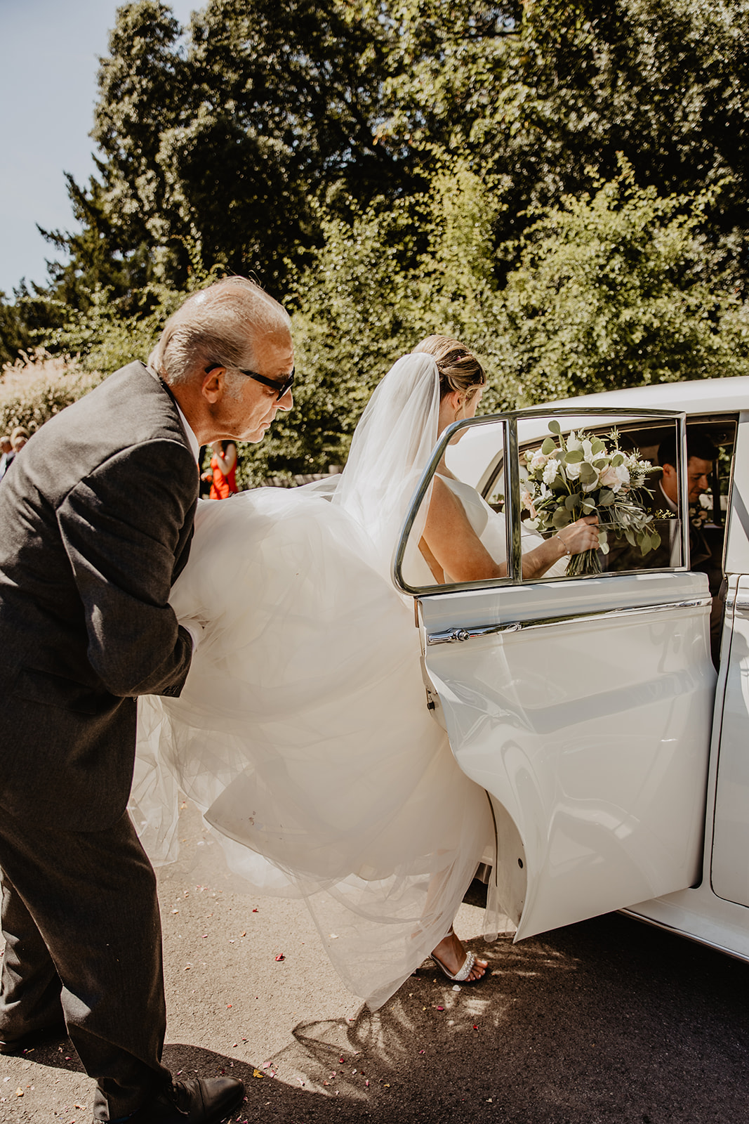 Bride getting in wedding car at an RHS Gardens Wisley Wedding. By Olive Joy Photography