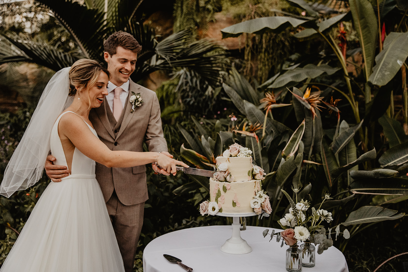 Bride and groom cutting the cake at a RHS Gardens Wisley Wedding. By Olive Joy Photography