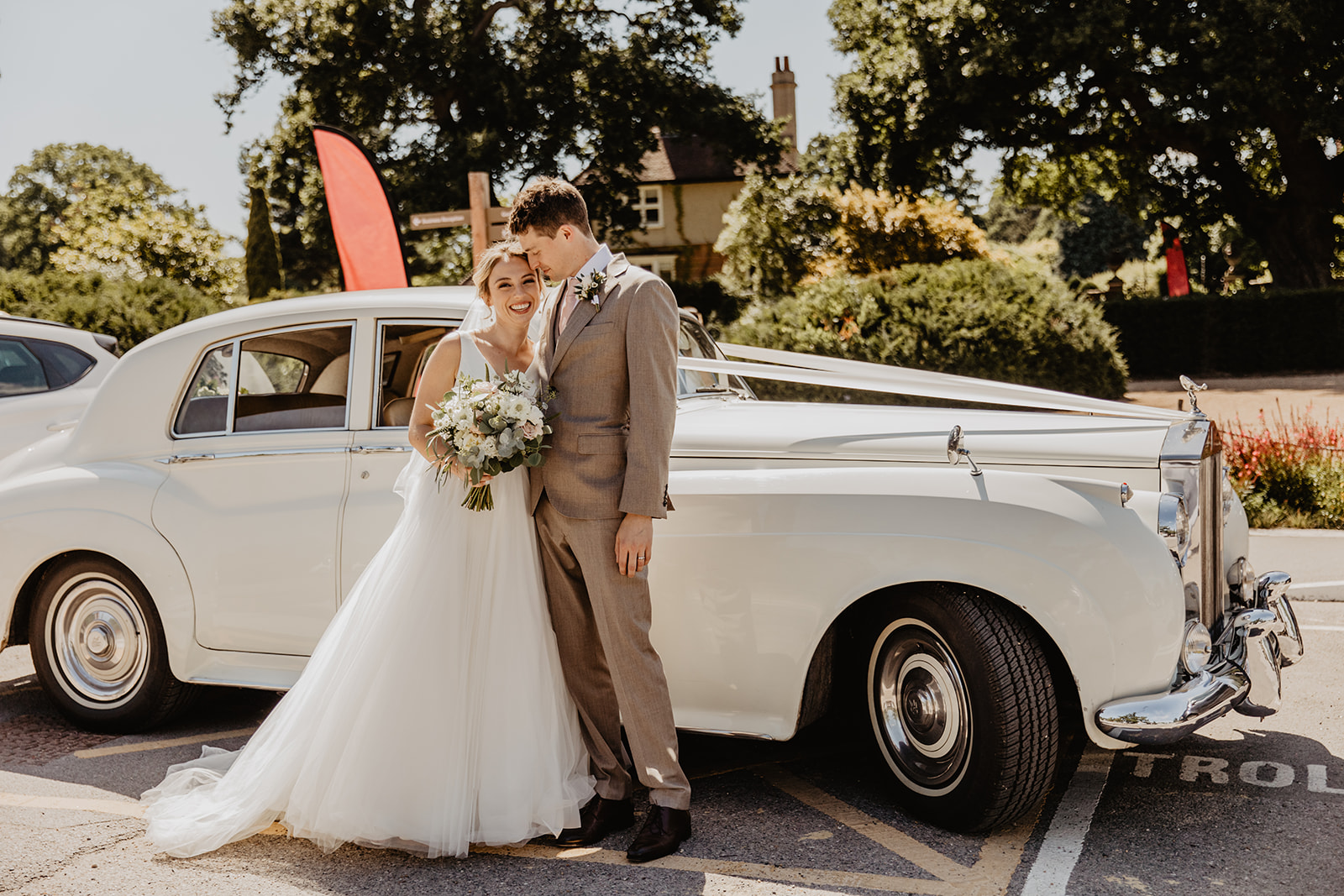 Bride and Groom standing by their wedding car at an RHS Gardens Wisley Wedding. By Olive Joy Photography