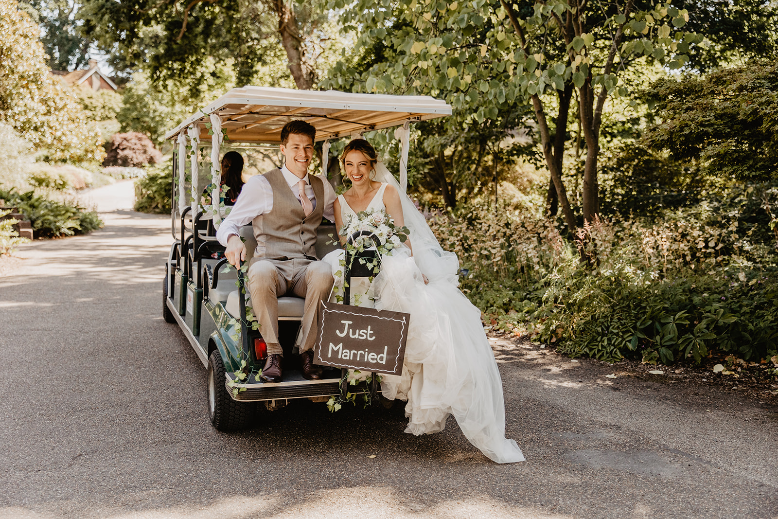 Bride and groom their 'just married' buggy at a RHS Gardens Wisley Wedding. By Olive Joy Photography