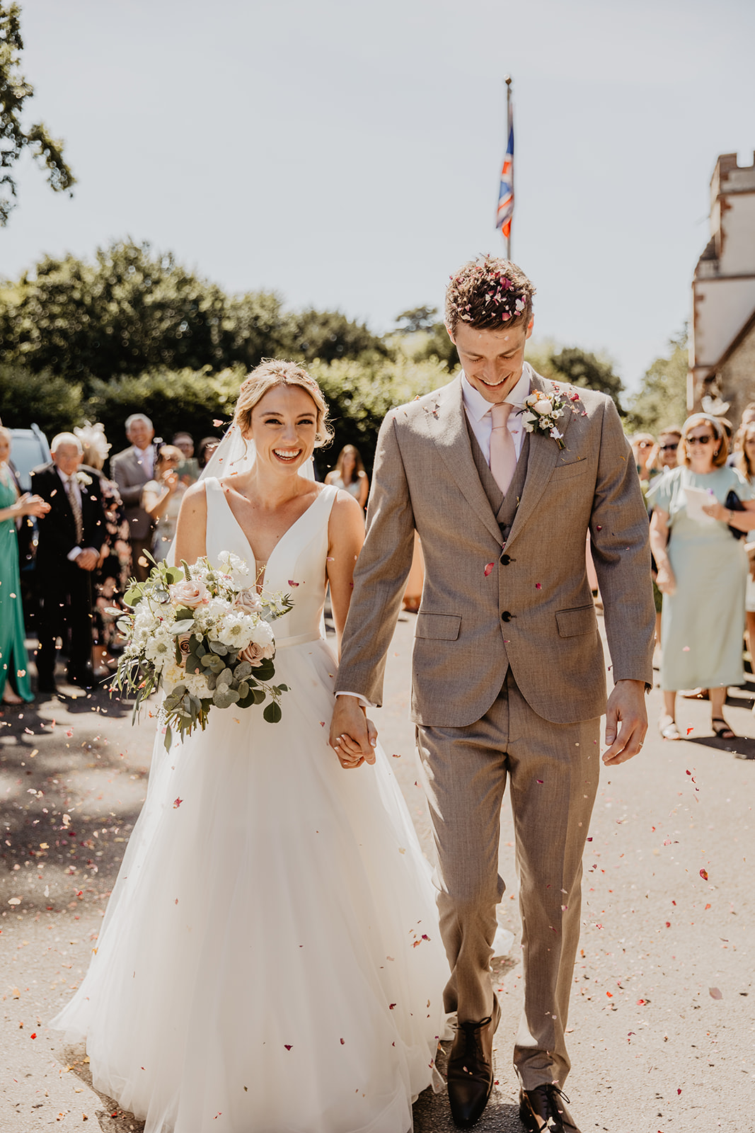 Bride and Groom under confetti at an RHS Gardens Wisley Wedding. By Olive Joy Photography